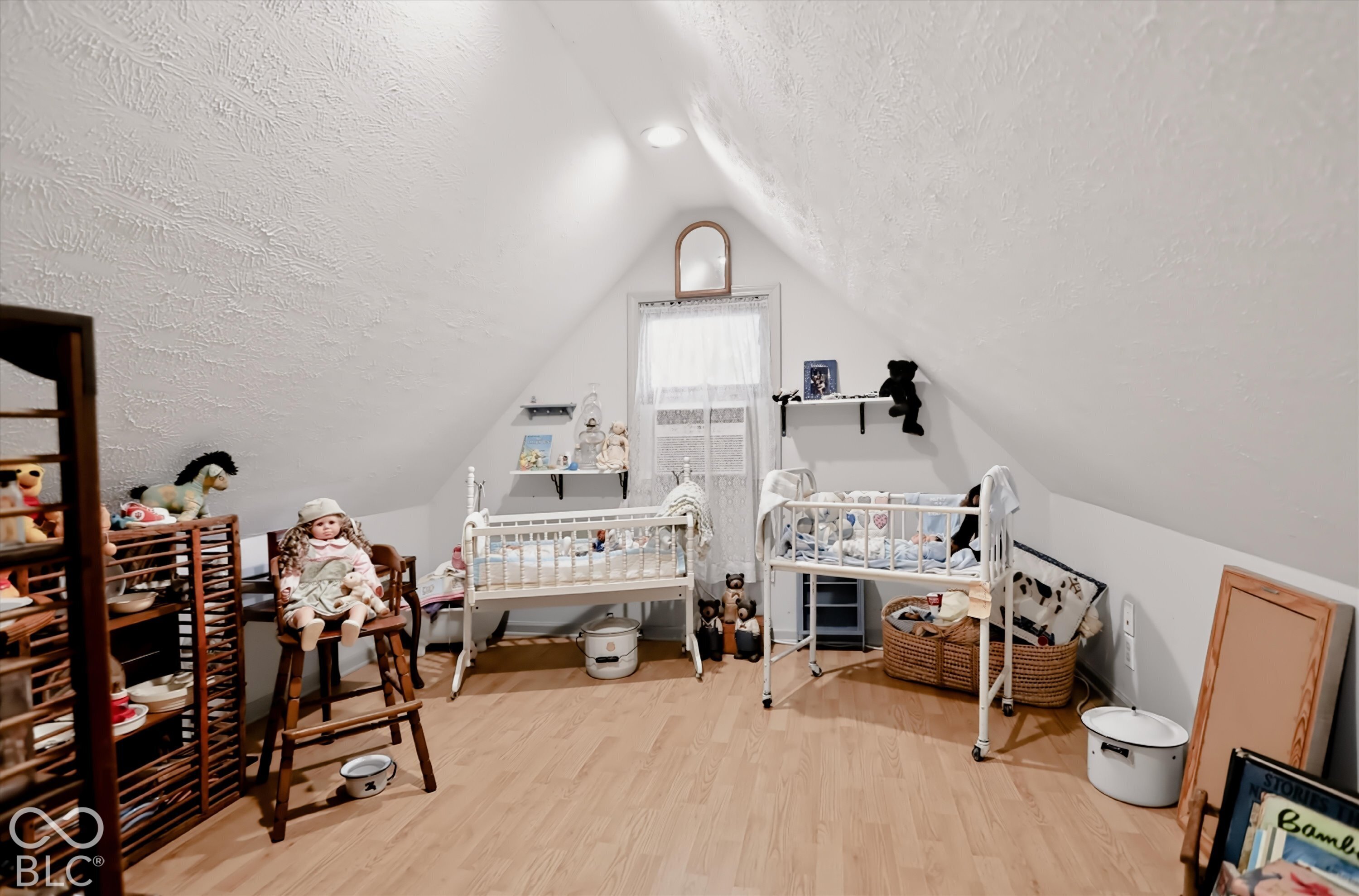 Attic room featuring a peaked ceiling, wood-finish flooring, recessed lighting, and a window with a centered arch-top mirror
