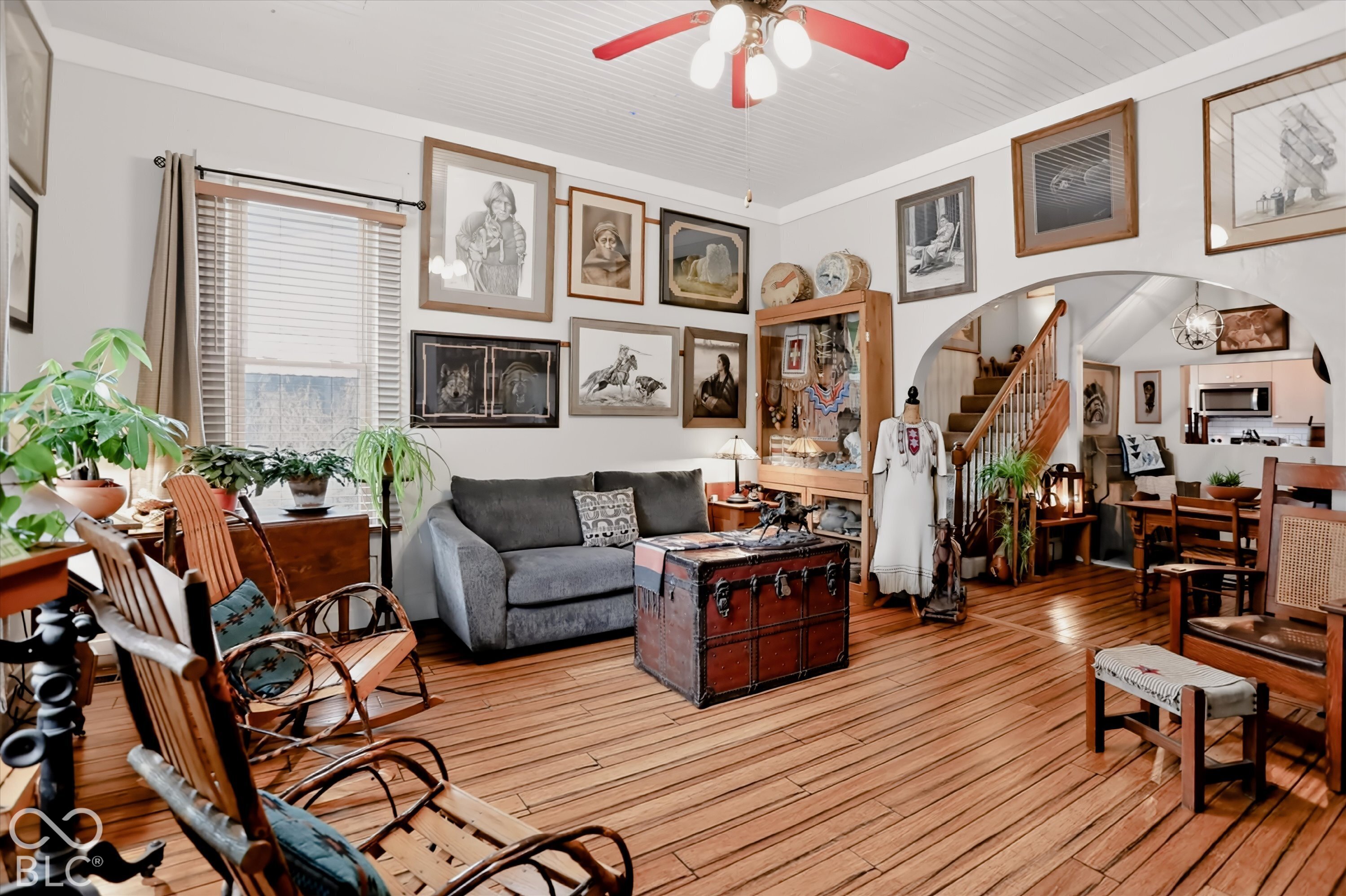 Hardwood flooring, wood-paneled ceiling, built-in display cabinetry, arched doorway, and staircase with wooden banister