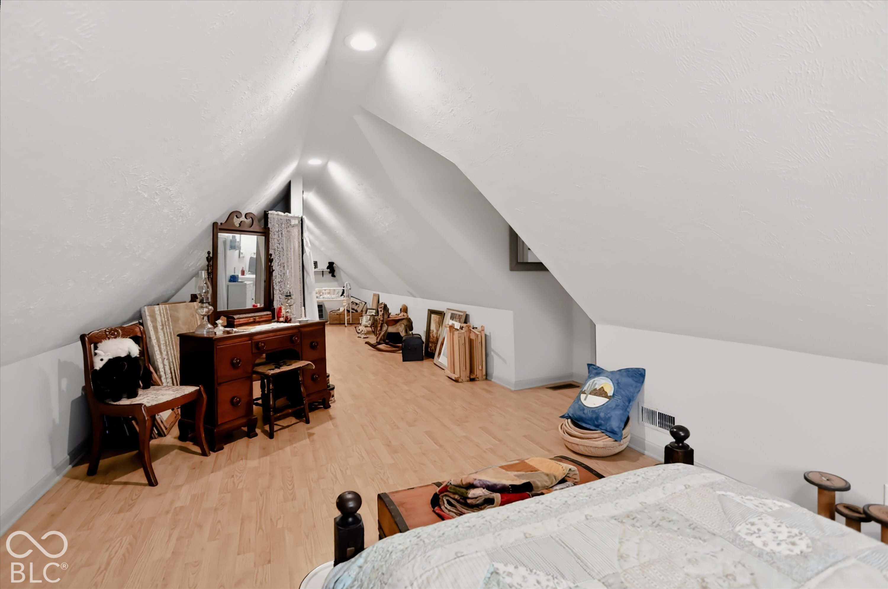 Attic space with sloped ceilings, wood-finish flooring, and recessed lighting