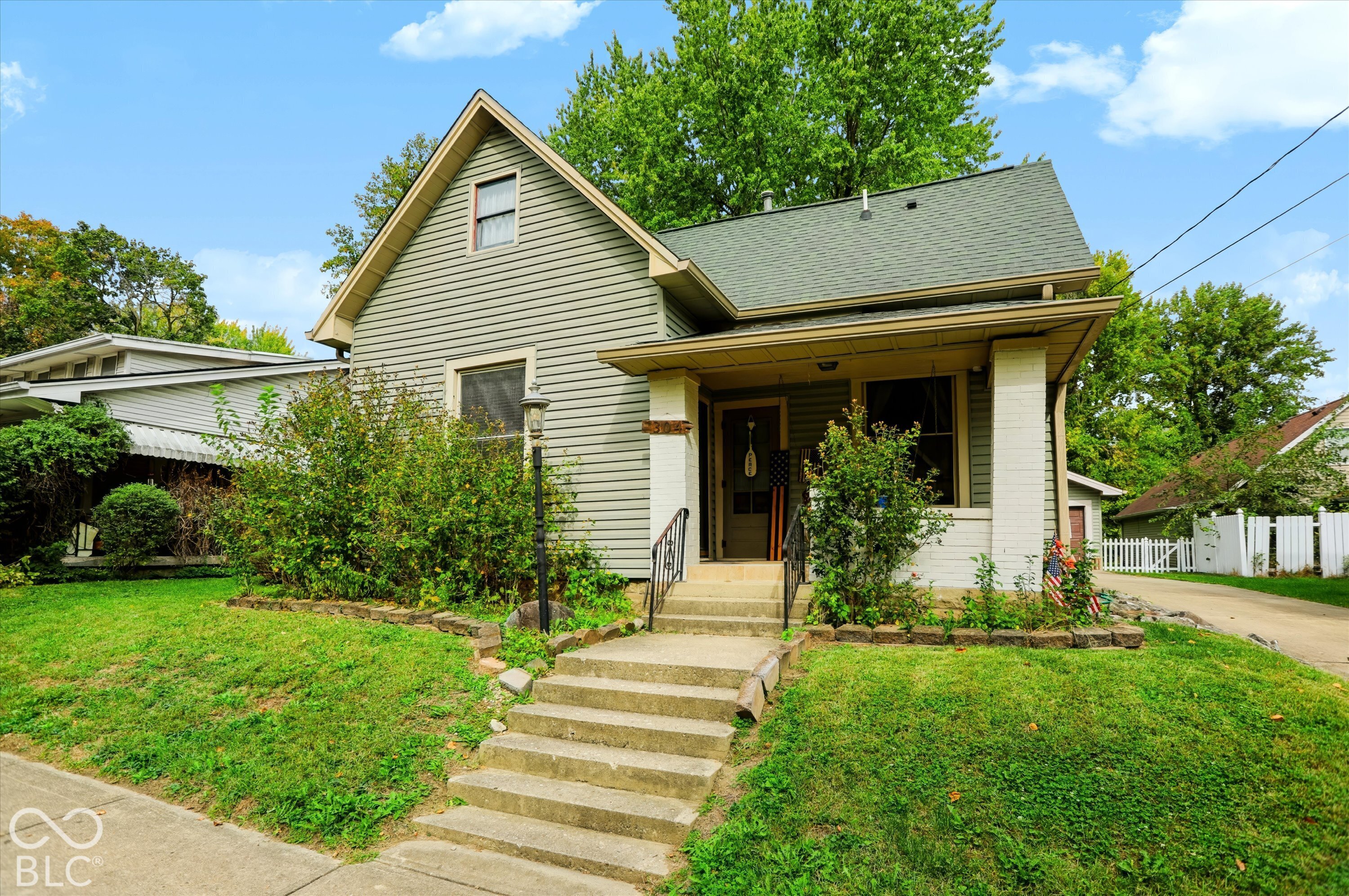 Exterior featuring horizontal siding, a covered front porch with masonry column supports, concrete steps, and a gabled roofline