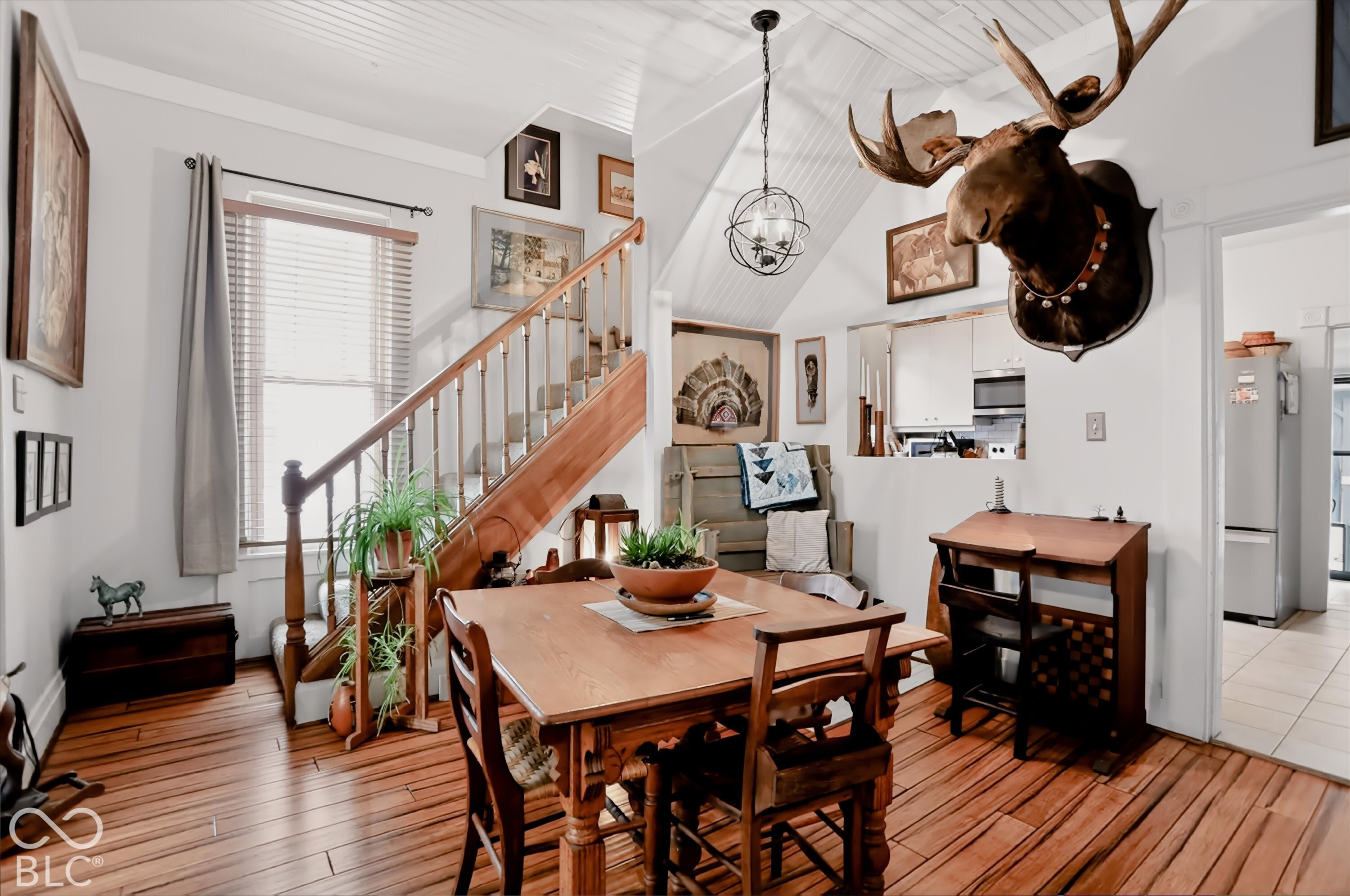 Interior space featuring wood-finish flooring, a wood-railed staircase, beadboard ceiling, and a spherical metal pendant light fixture