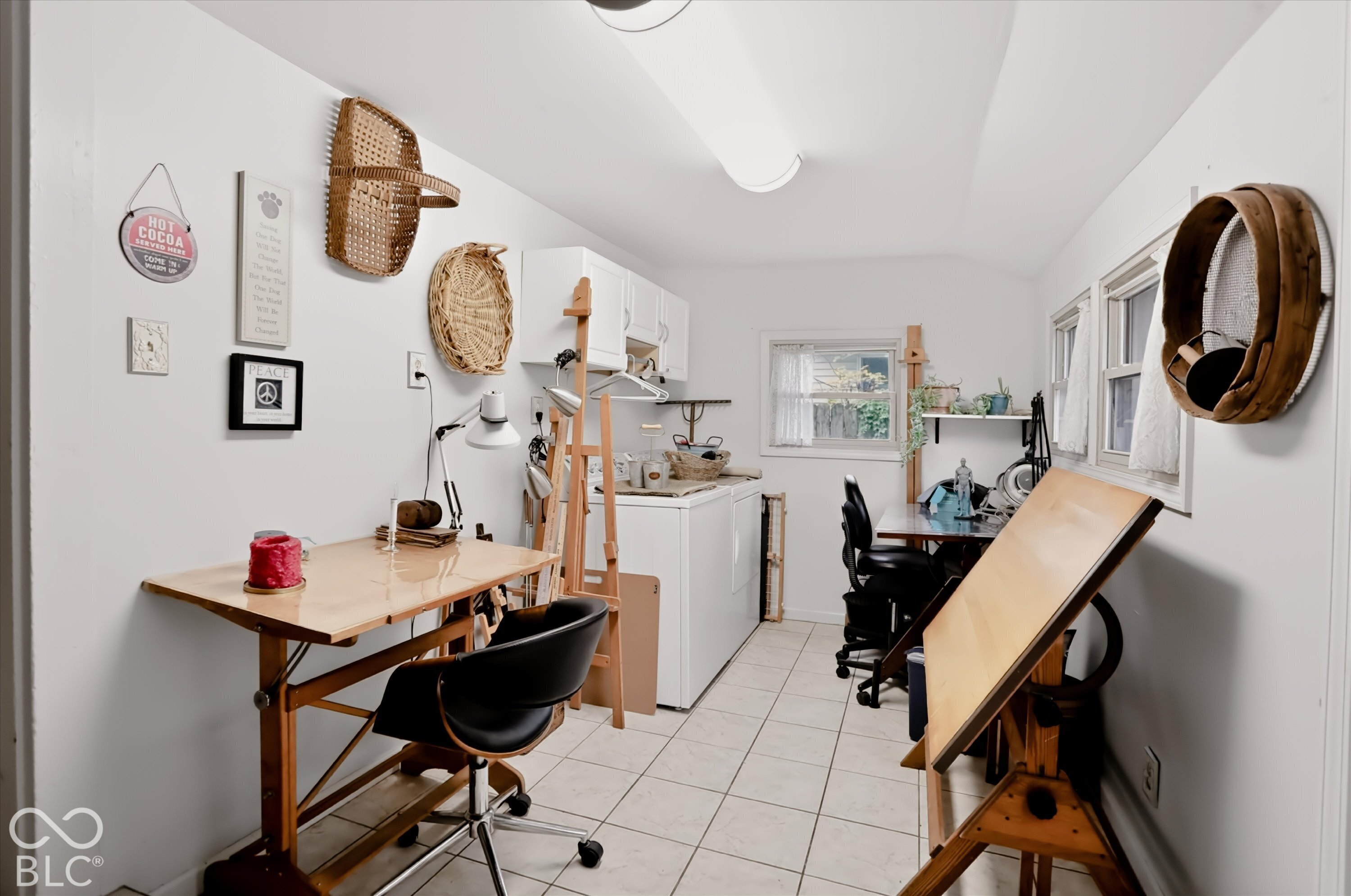 Tile flooring, white wall-mounted cabinetry, integrated laundry appliances, linear fluorescent lighting, and two operable windows
