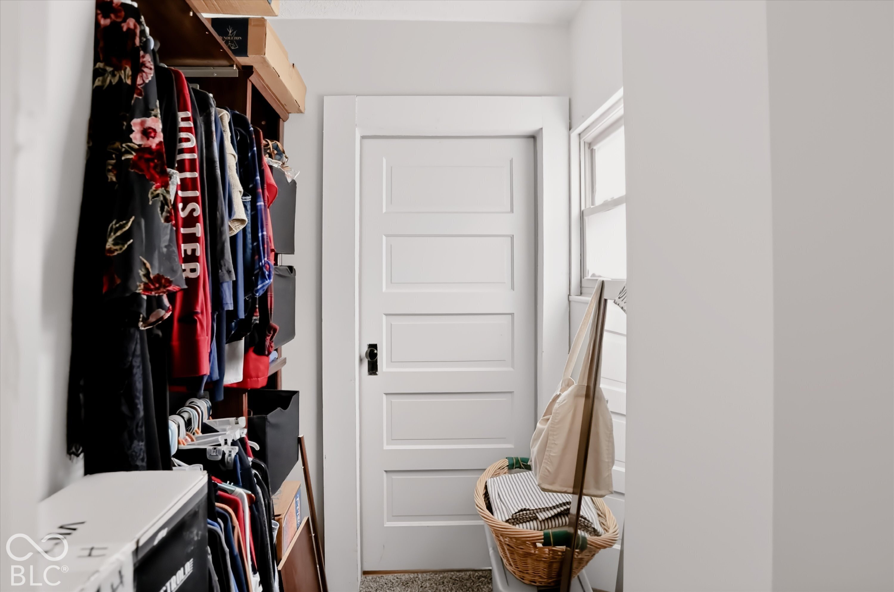 Five-panel solid core door with matte black hardware, featuring a wooden built-in shelving unit and a window with white trim
