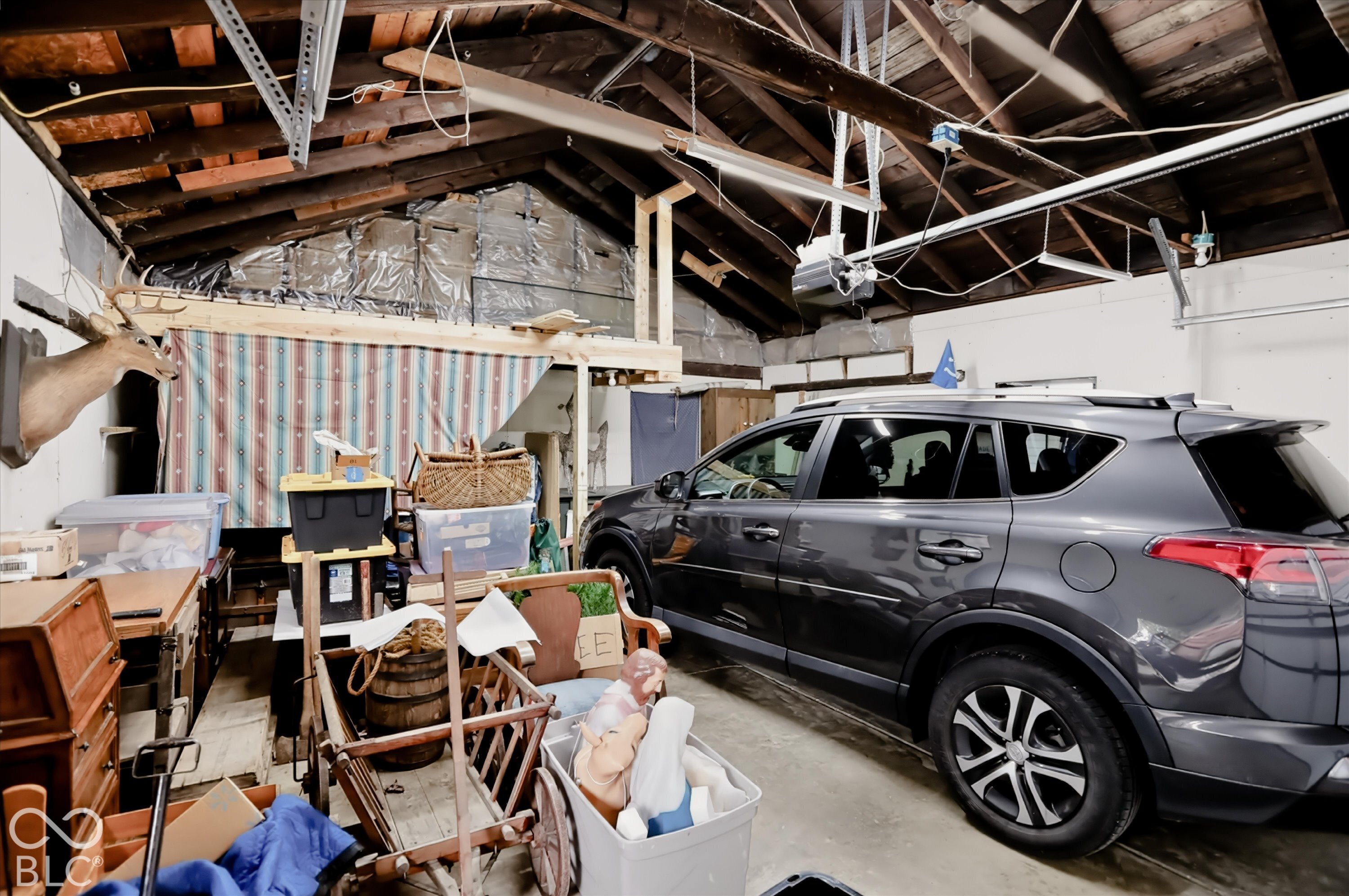 Garage space featuring exposed timber rafters, a concrete floor, and overhead garage door opener