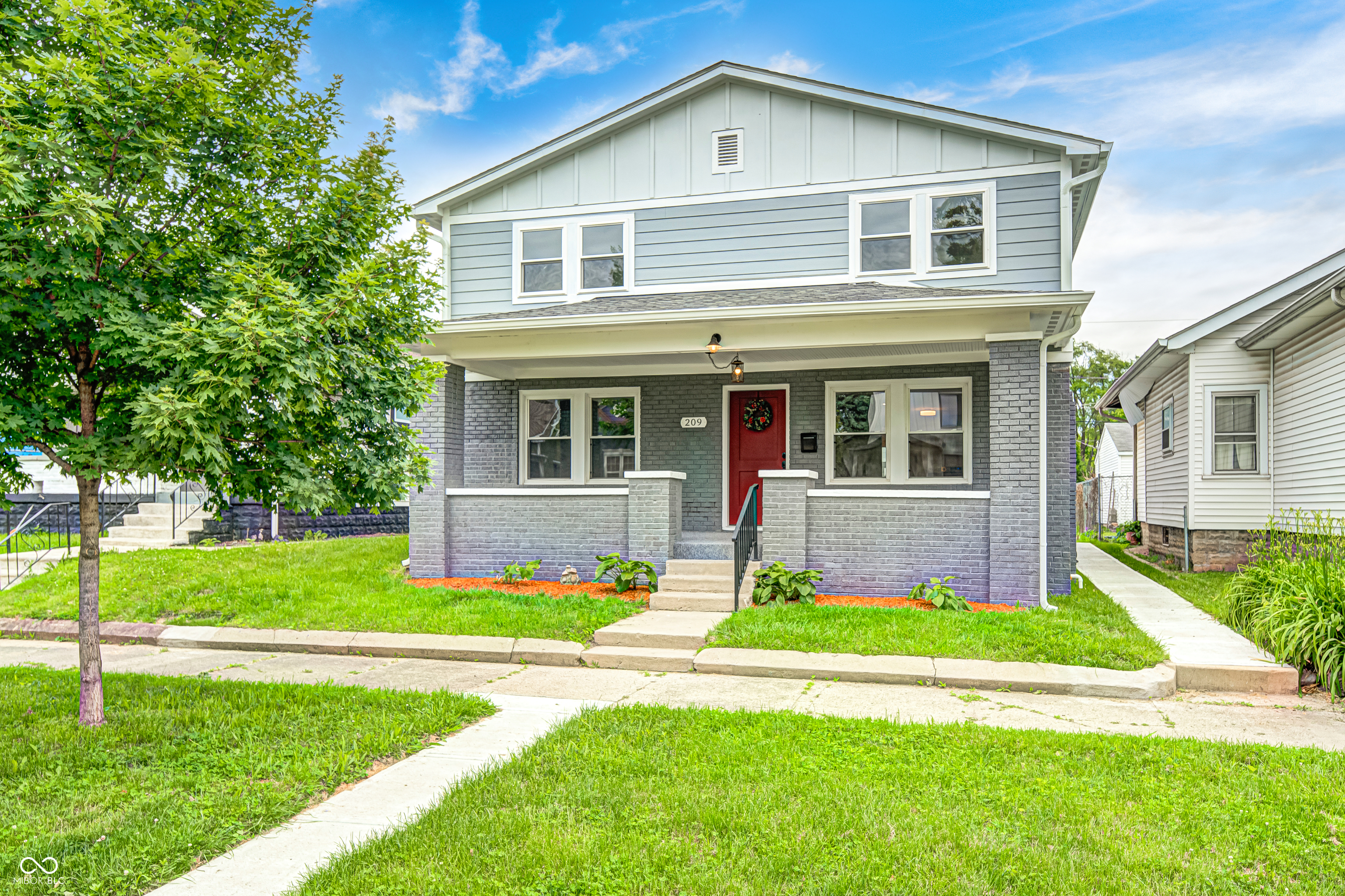 Two-story residence featuring a gray brick foundation, light blue siding, and a red front door