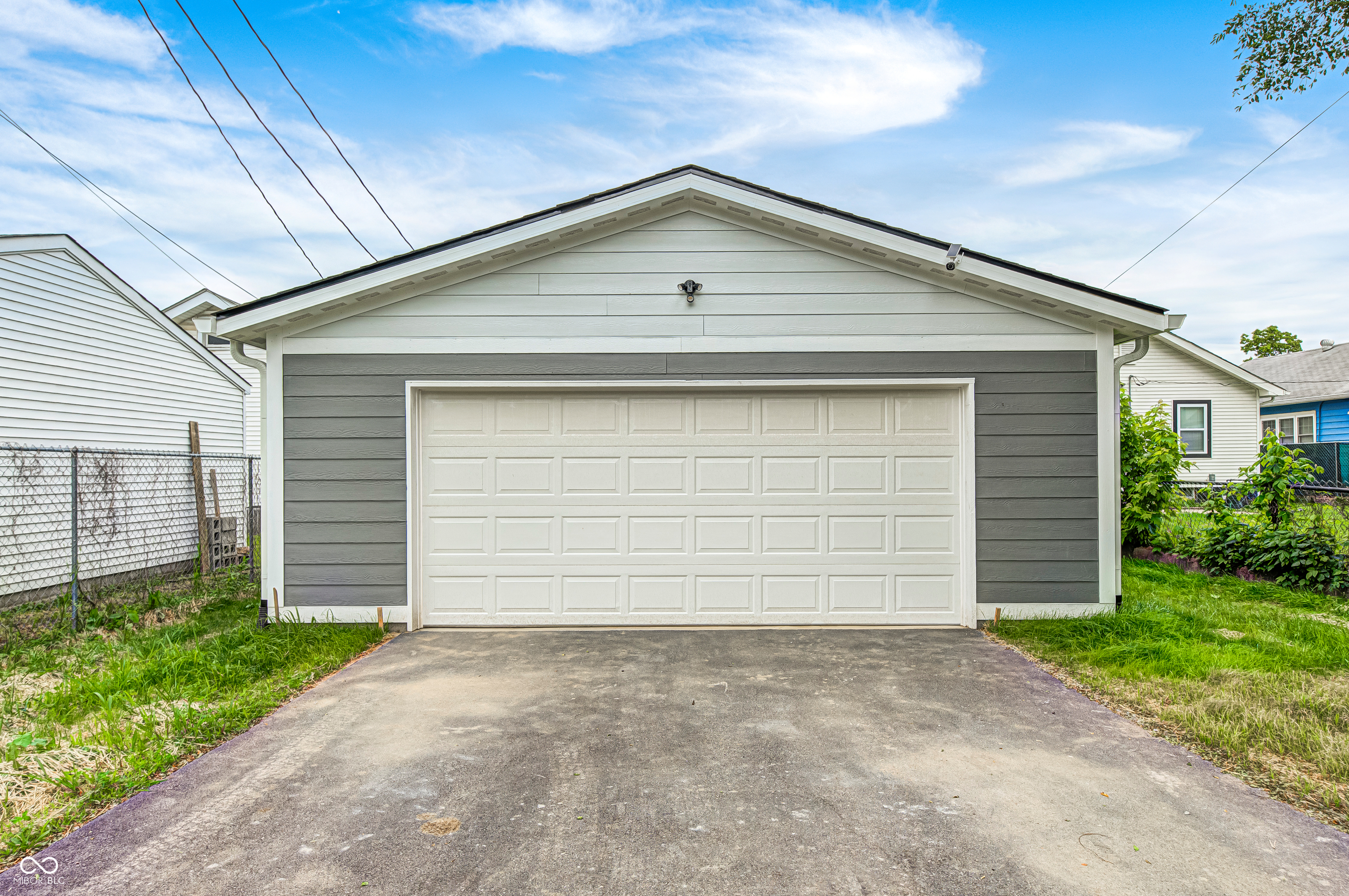 Detached two-car garage featuring a white paneled door, gray horizontal siding, and white trim