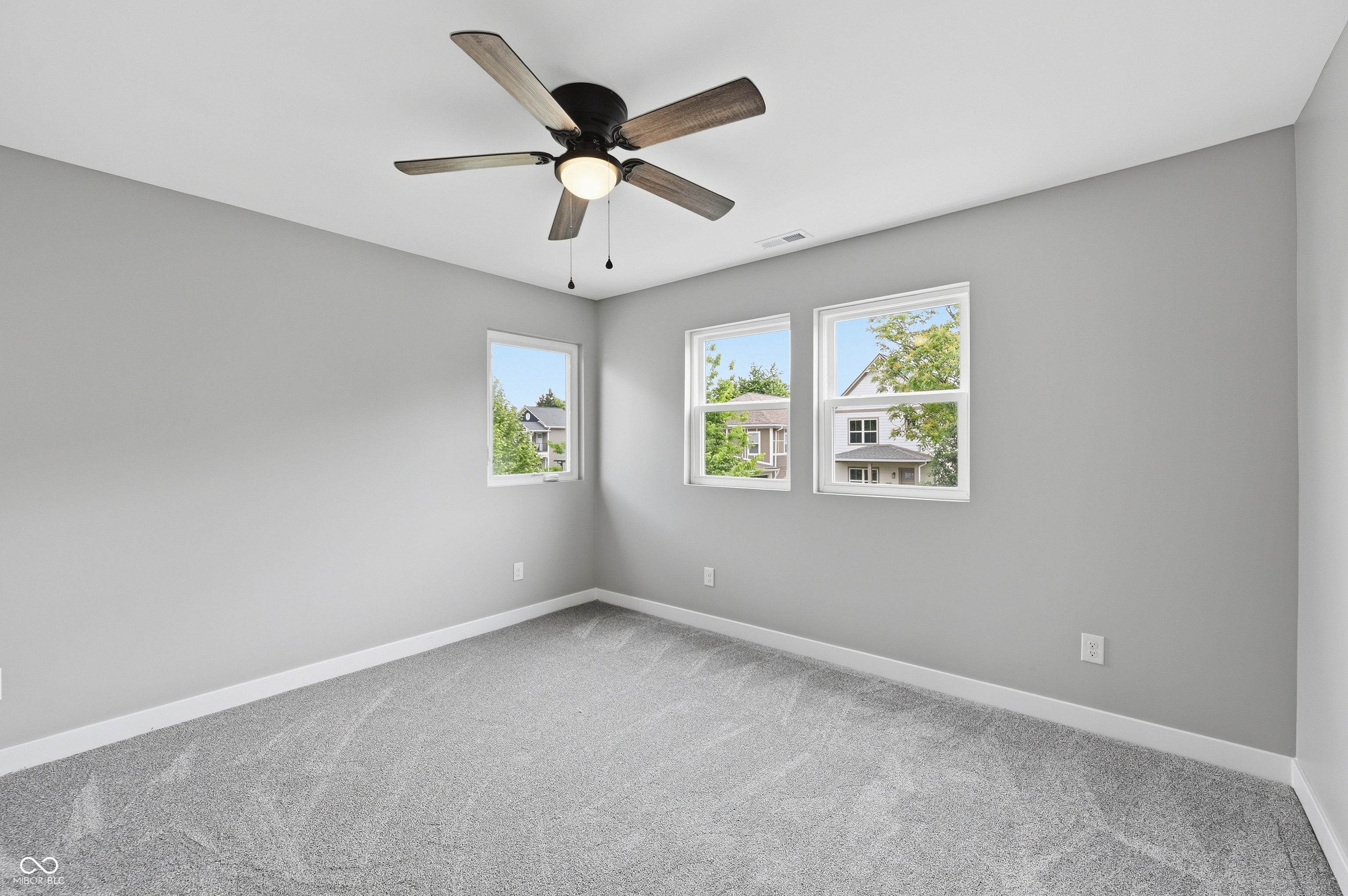 Neutral-toned room featuring a ceiling fan with light fixture, gray wall paint, and gray carpet flooring