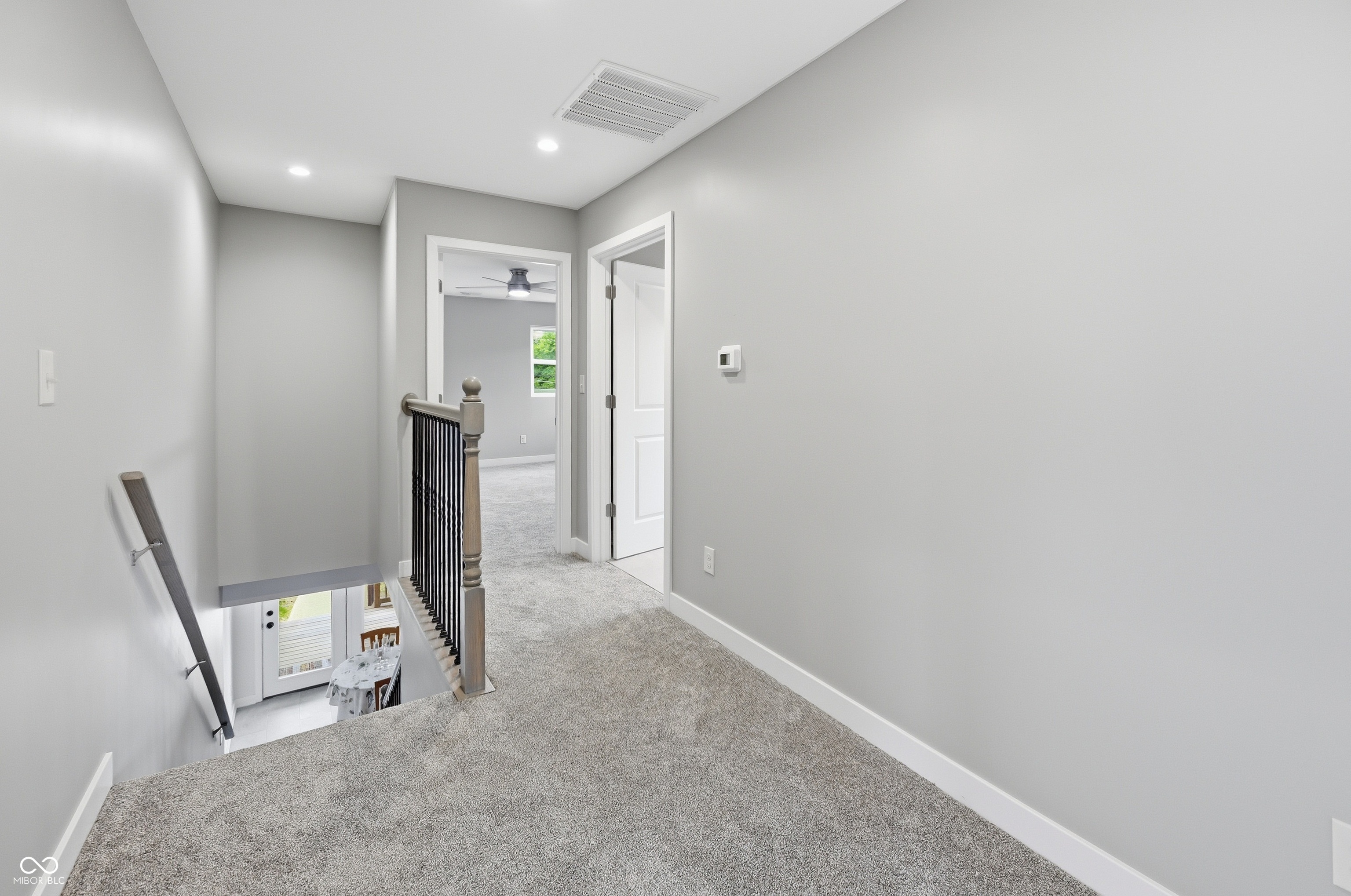 Carpeted upper hallway featuring light gray wall paint, white baseboards, and recessed lighting