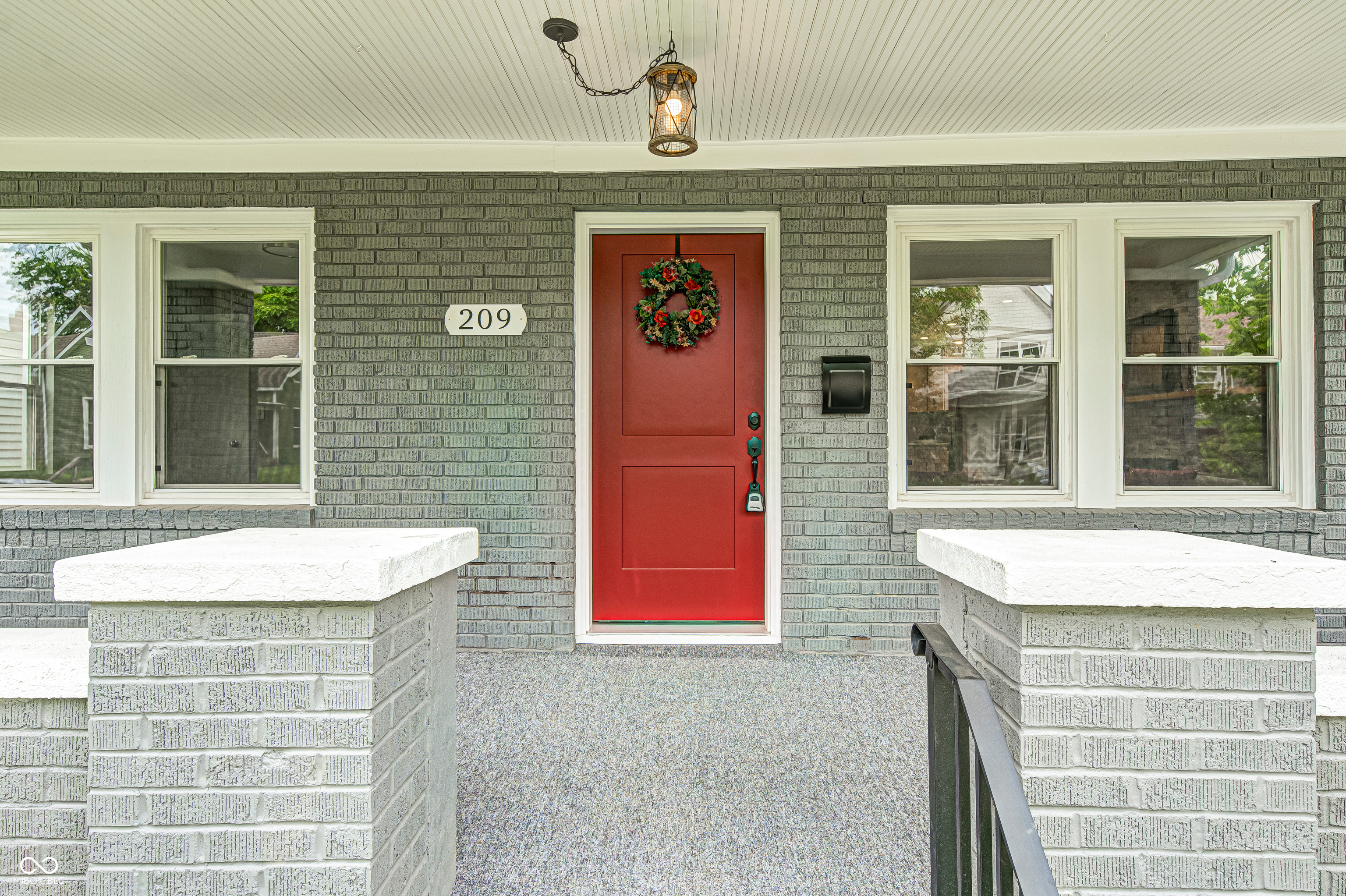 Inviting red entry door with sidelight window, framed by gray brick facade and white window trim