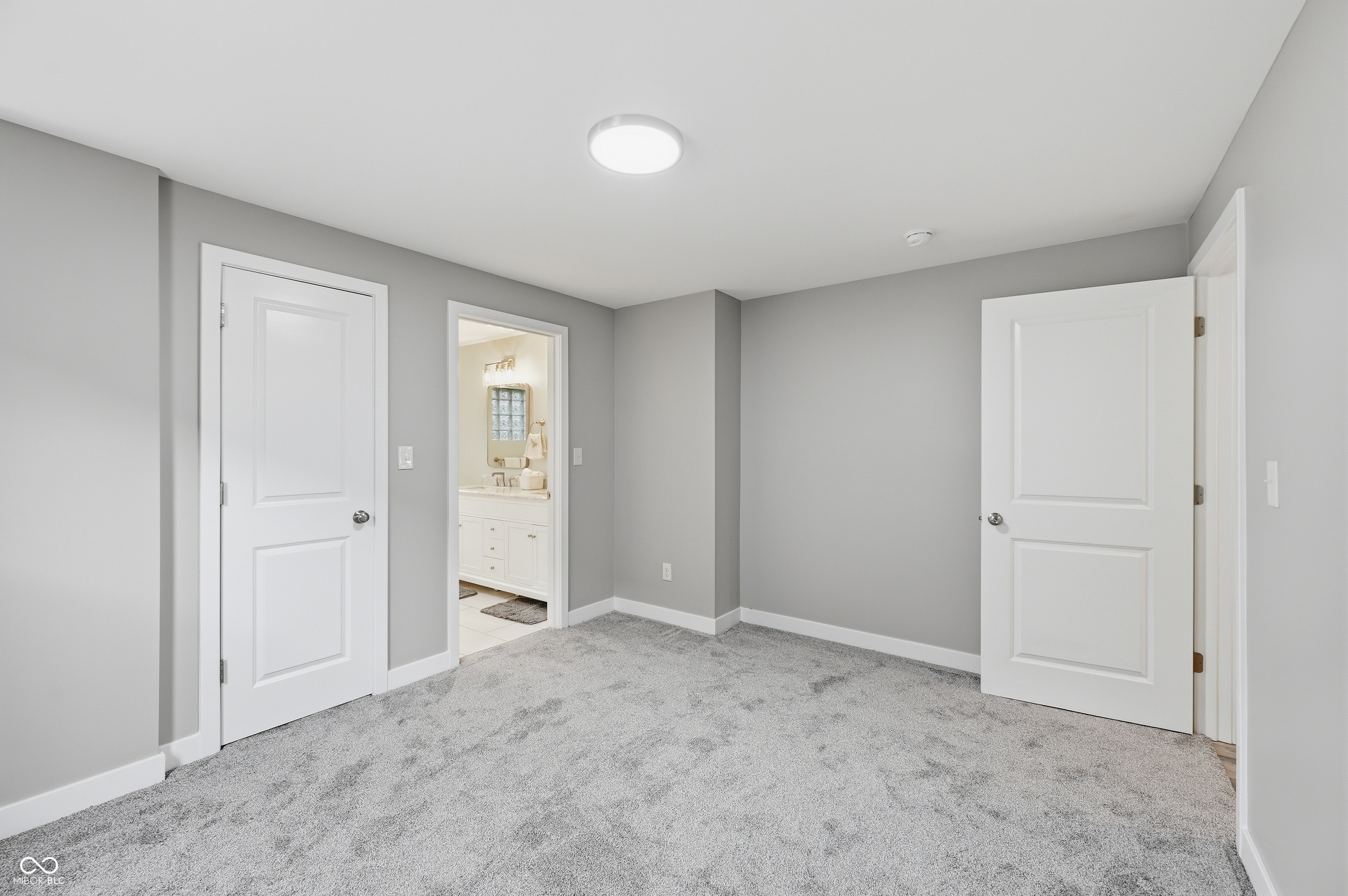 Interior room featuring light gray walls, white trim, and gray carpet flooring