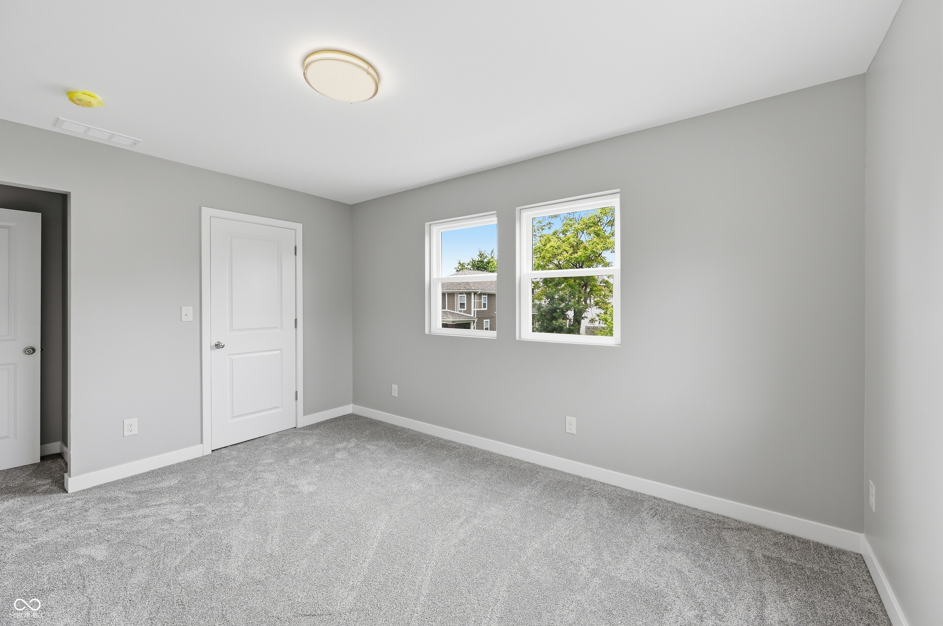 Light gray wall paint with white trim, gray carpet flooring, and a contemporary ceiling light fixture