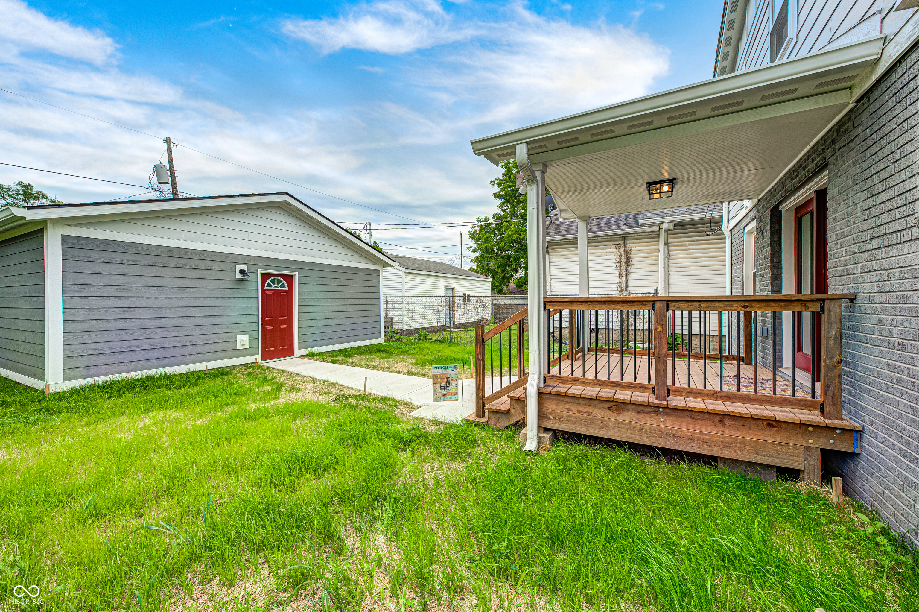Rear covered porch featuring wood decking and black metal balusters
