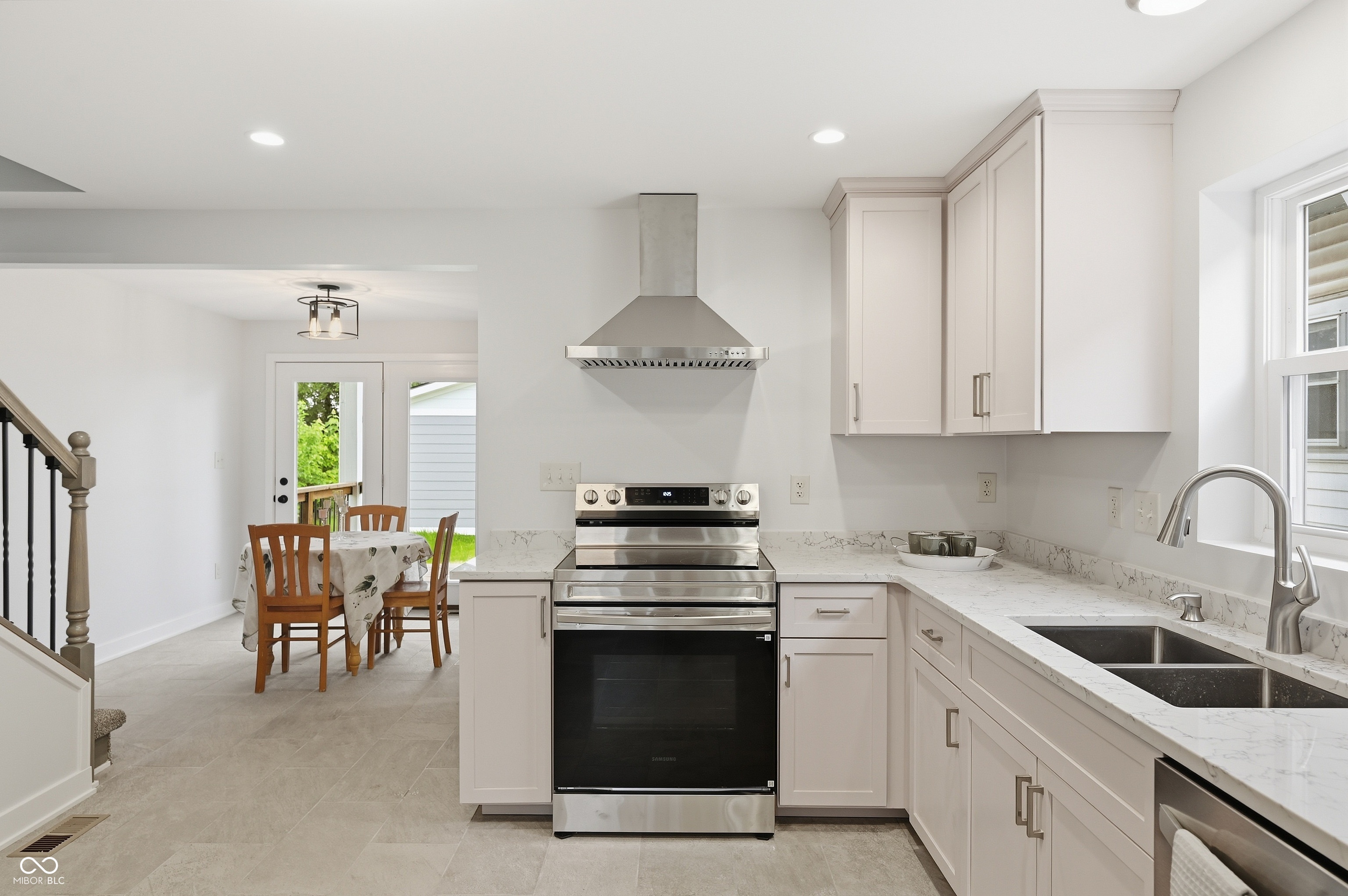 Contemporary kitchen featuring light-toned cabinetry, stainless steel appliances, a double basin sink, and ample countertop space