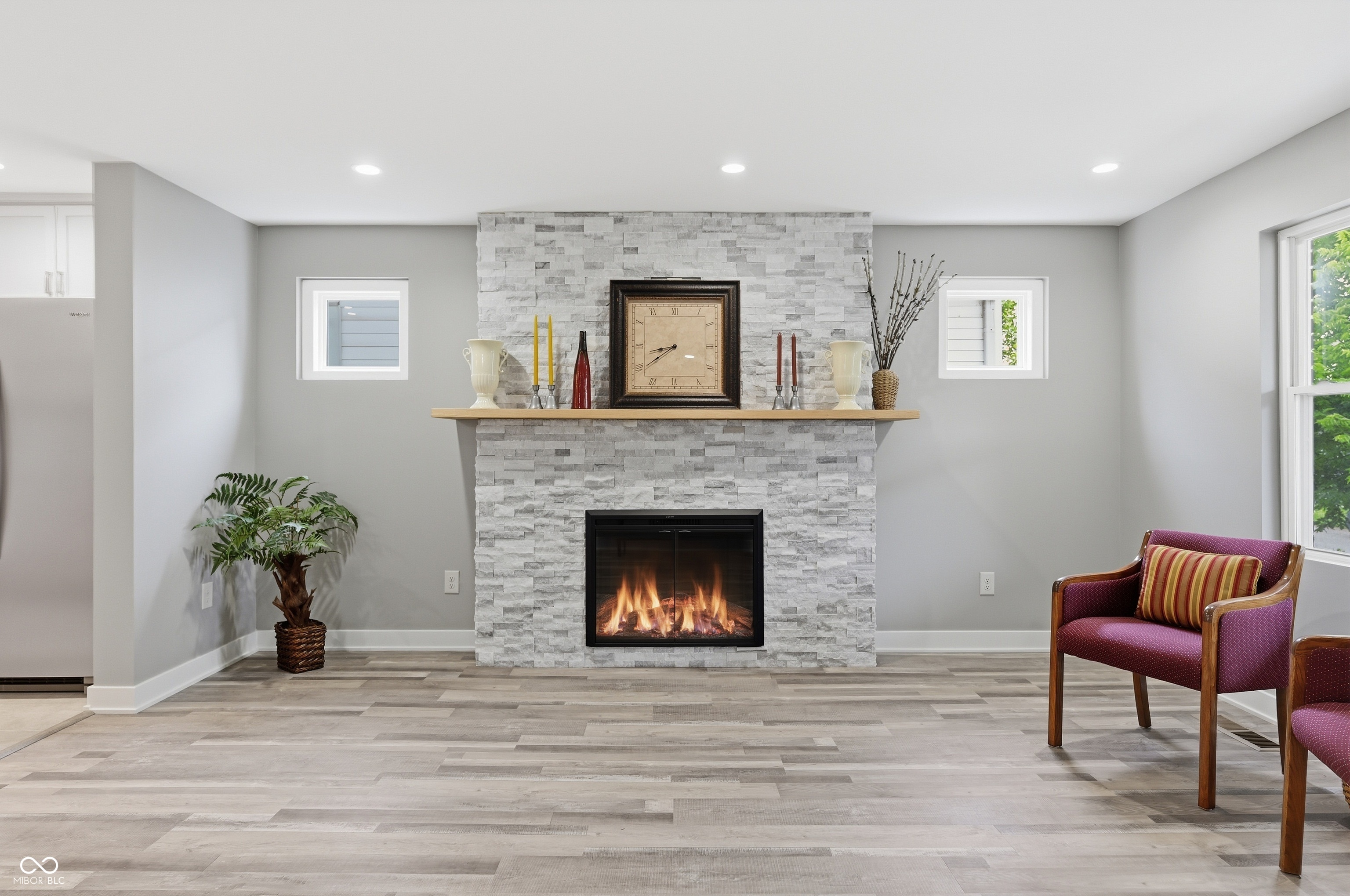 Stone-clad fireplace with an integrated electric insert and a light wood mantel Stone-clad fireplace with an integrated electric insert and a light wood mantel