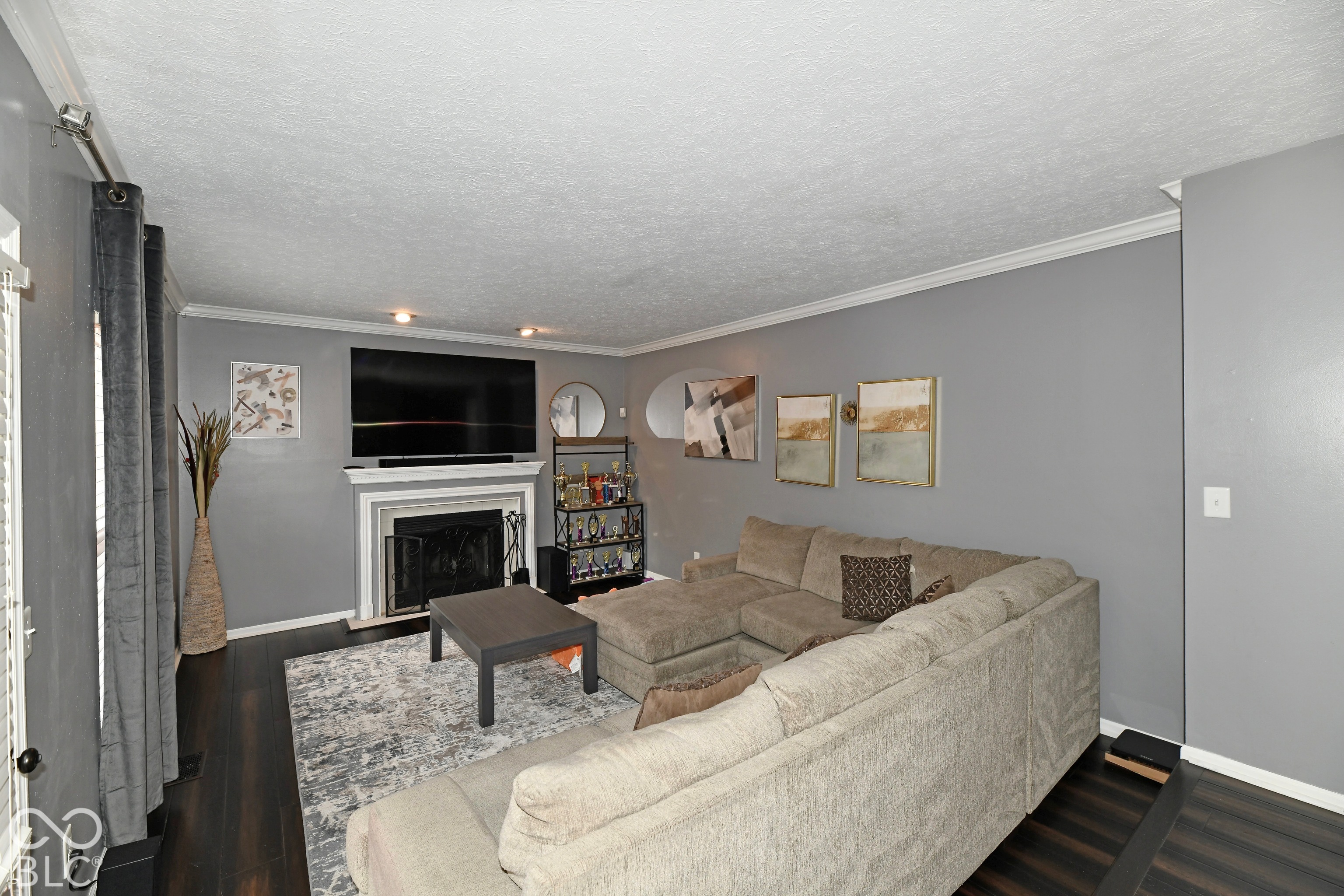 Interior space featuring dark wood-finish flooring, crown molding, and a fireplace with a decorative mantel