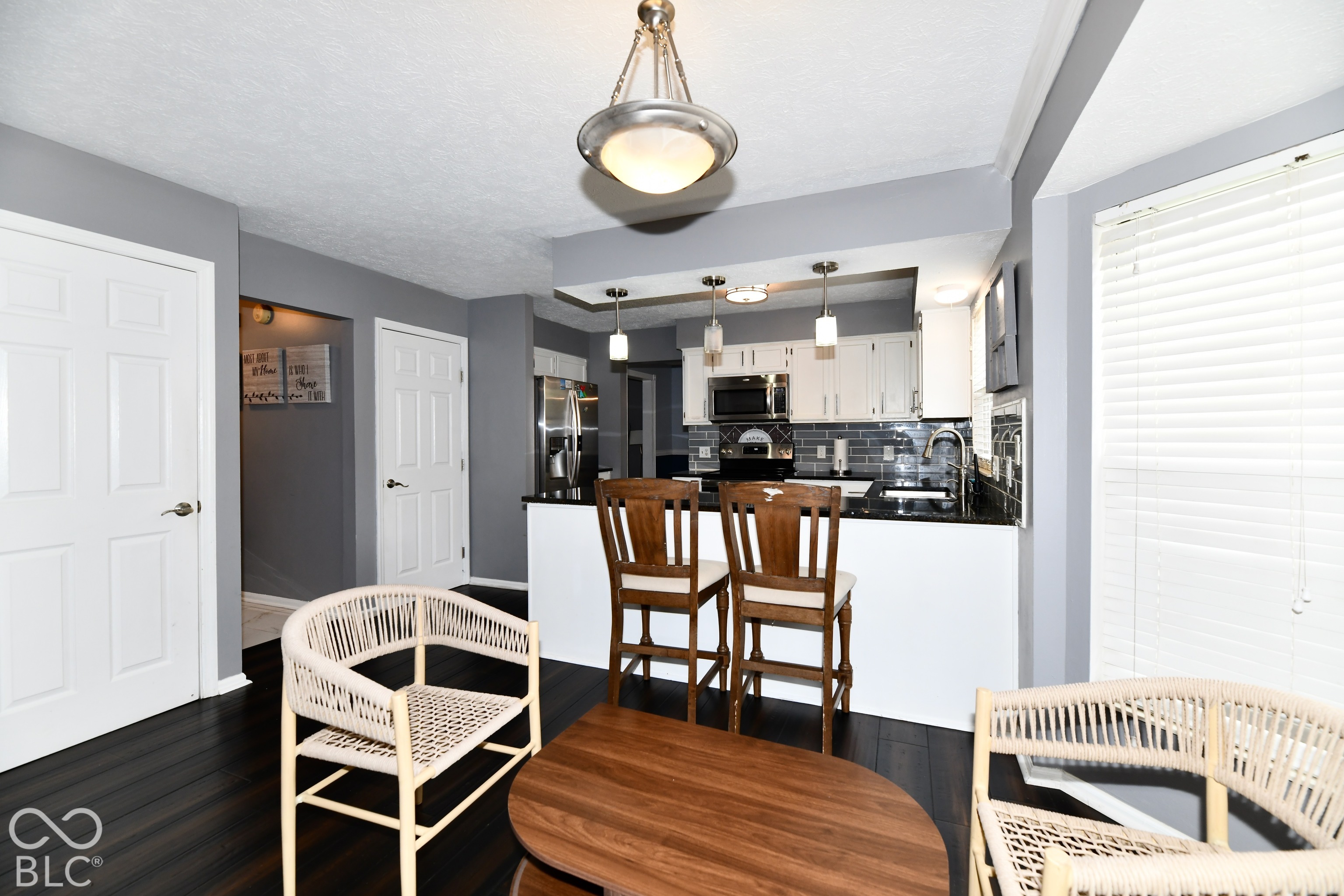 Kitchen featuring white cabinetry, dark countertops, a subway tile backsplash, stainless steel appliances, and wood-finish flooring