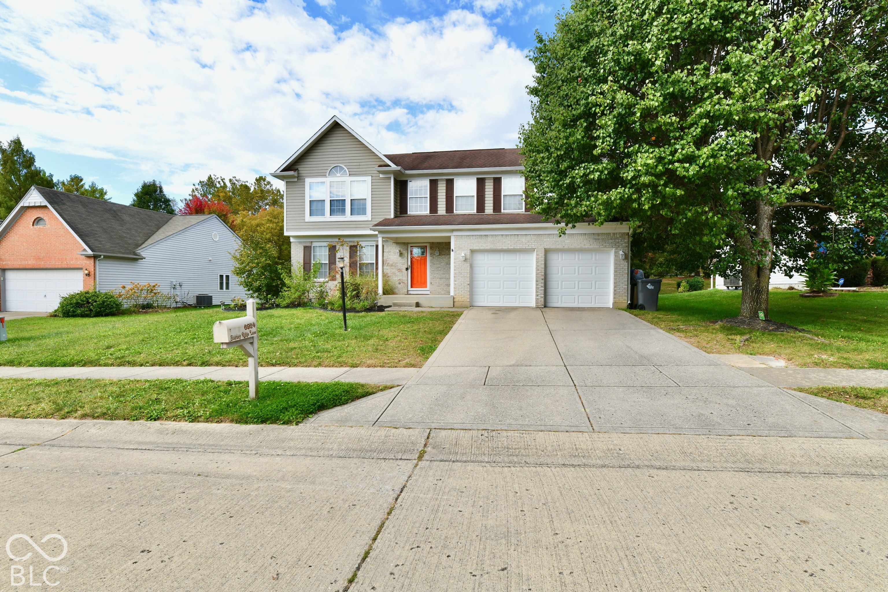 Two-story residence featuring a mixed brick and horizontal siding facade, attached two-car garage, concrete driveway, and front lawn Two-story residence featuring a mixed brick and horizontal siding facade, attached two-car garage, concrete driveway, and front lawn