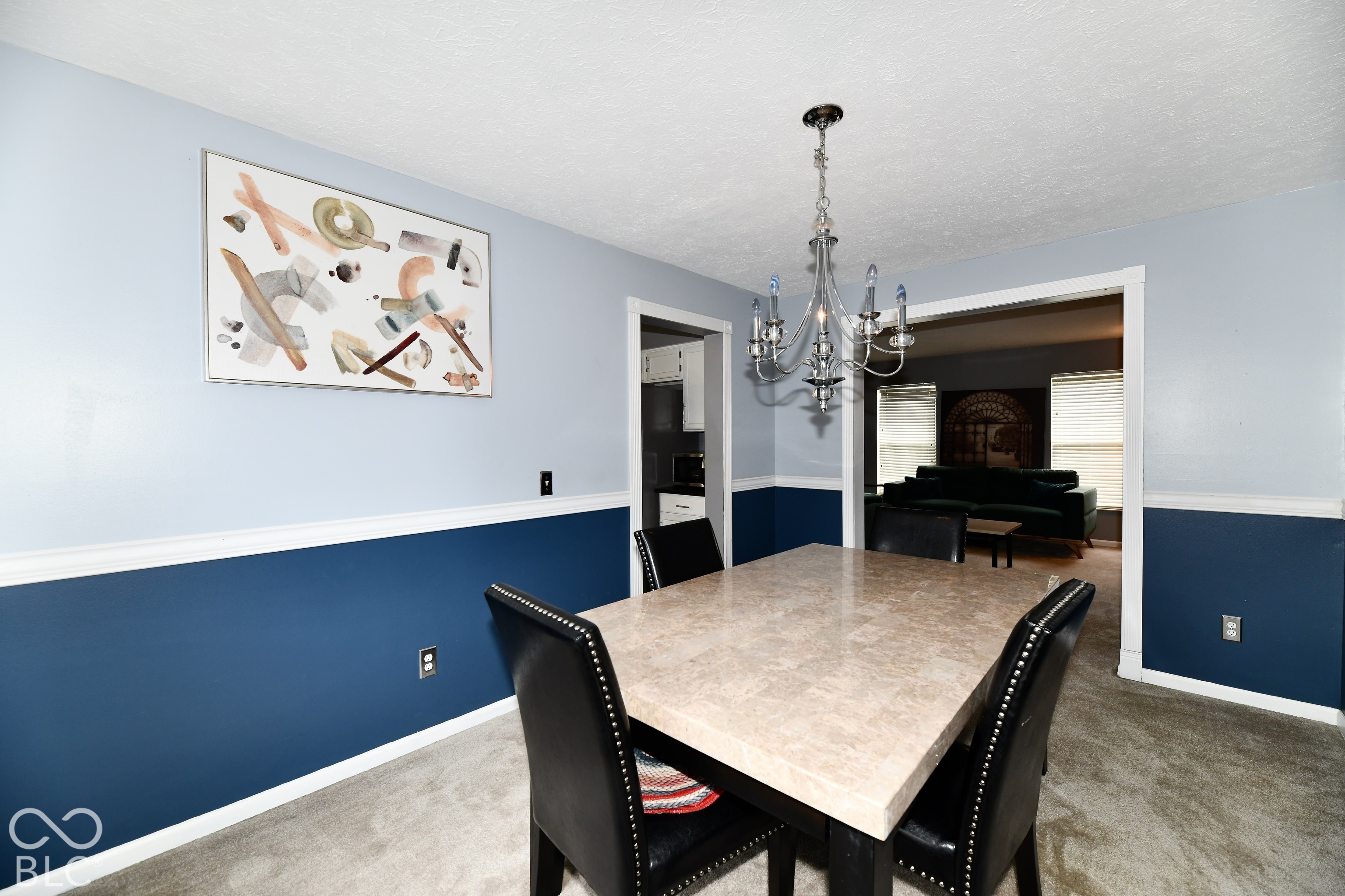 Dining area featuring dual-tone wall paint, waist-high chair rail molding, and a multi-arm decorative chandelier