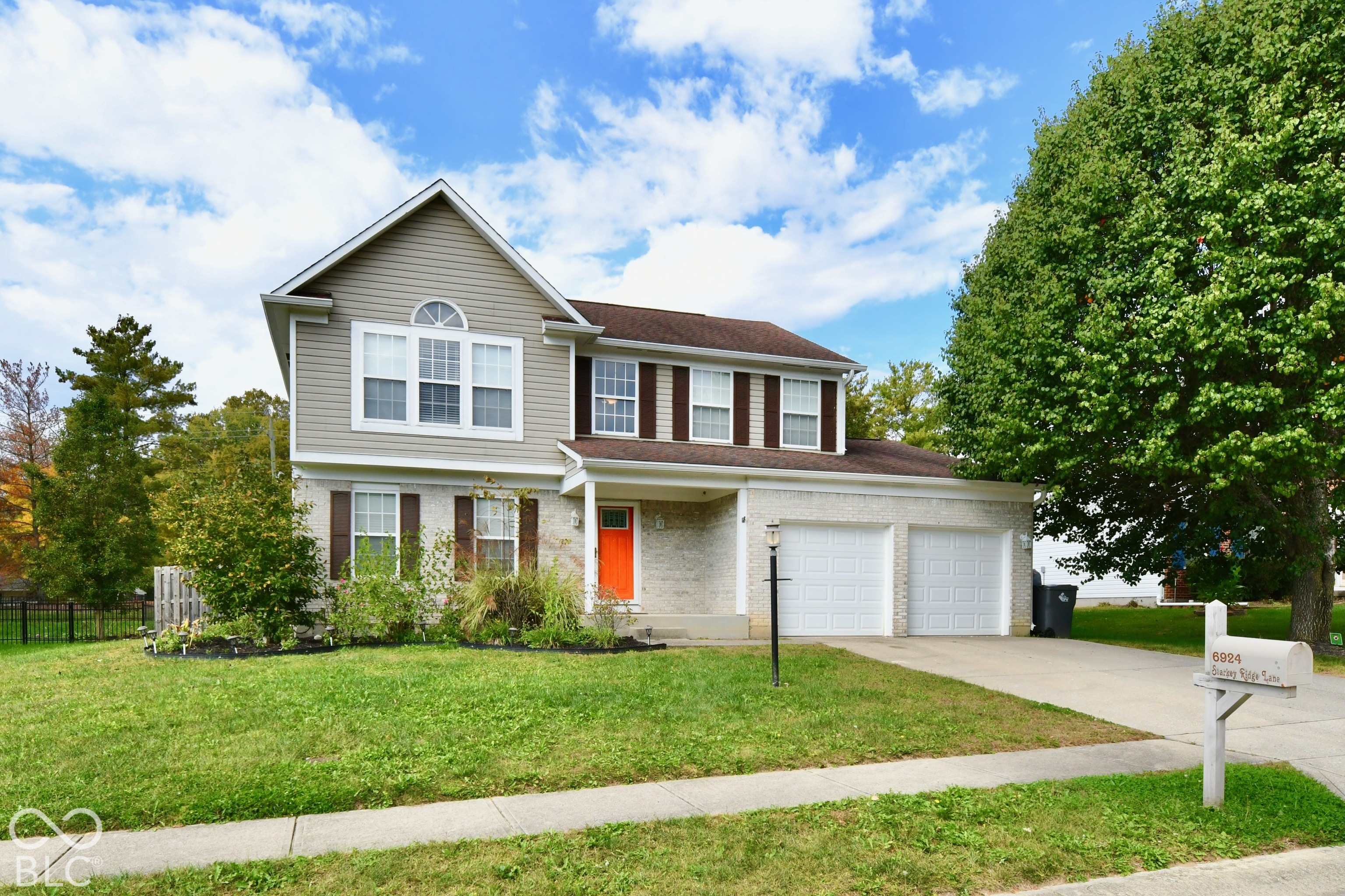 Two-story exterior featuring a brick and horizontal siding facade, a covered front porch, a two-car garage, and multiple paneled windows with shutters Two-story exterior featuring a brick and horizontal siding facade, a covered front porch, a two-car garage, and multiple paneled windows with shutters