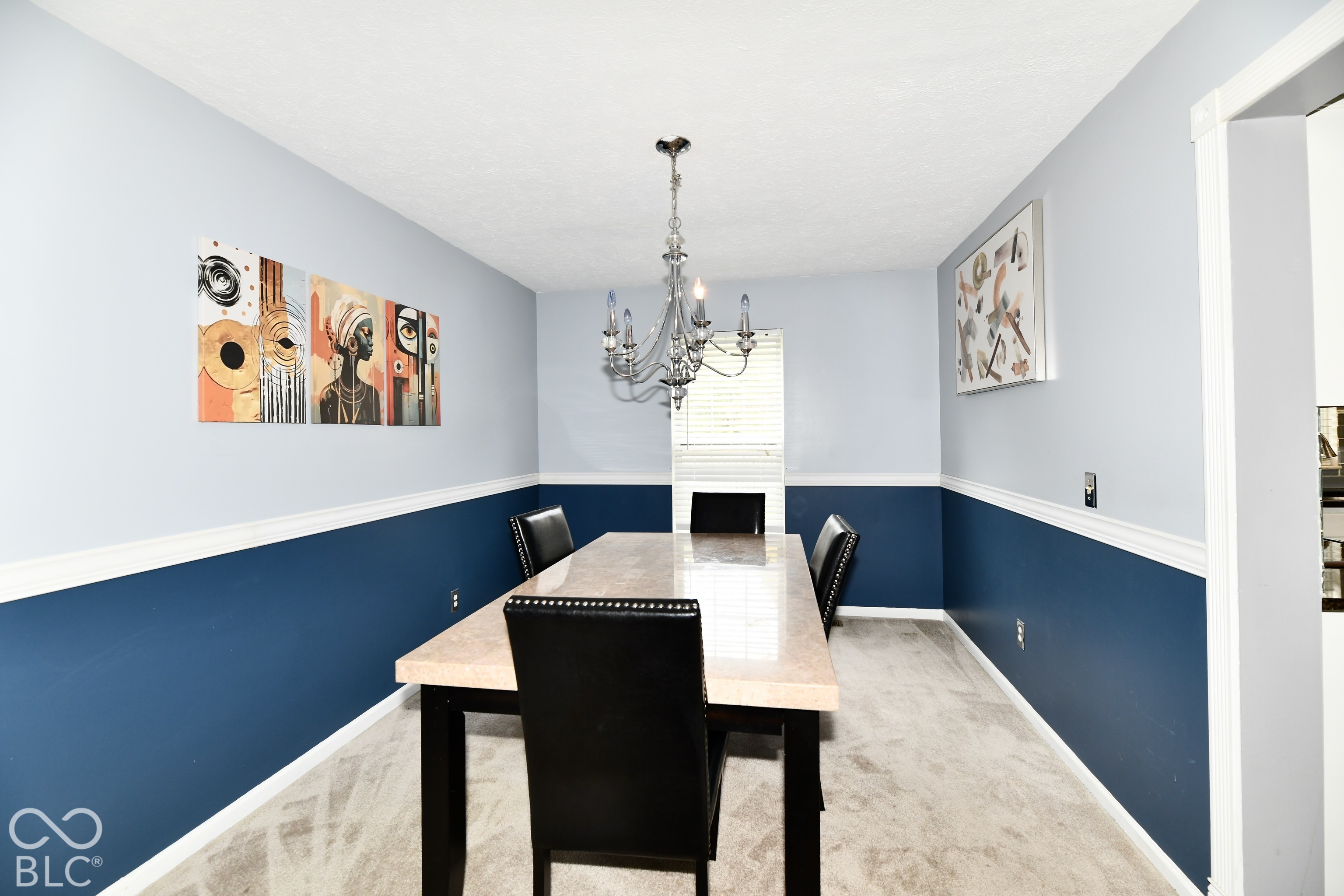 Dining area featuring two-tone wall paint, chair rail molding, and a multi-arm chandelier