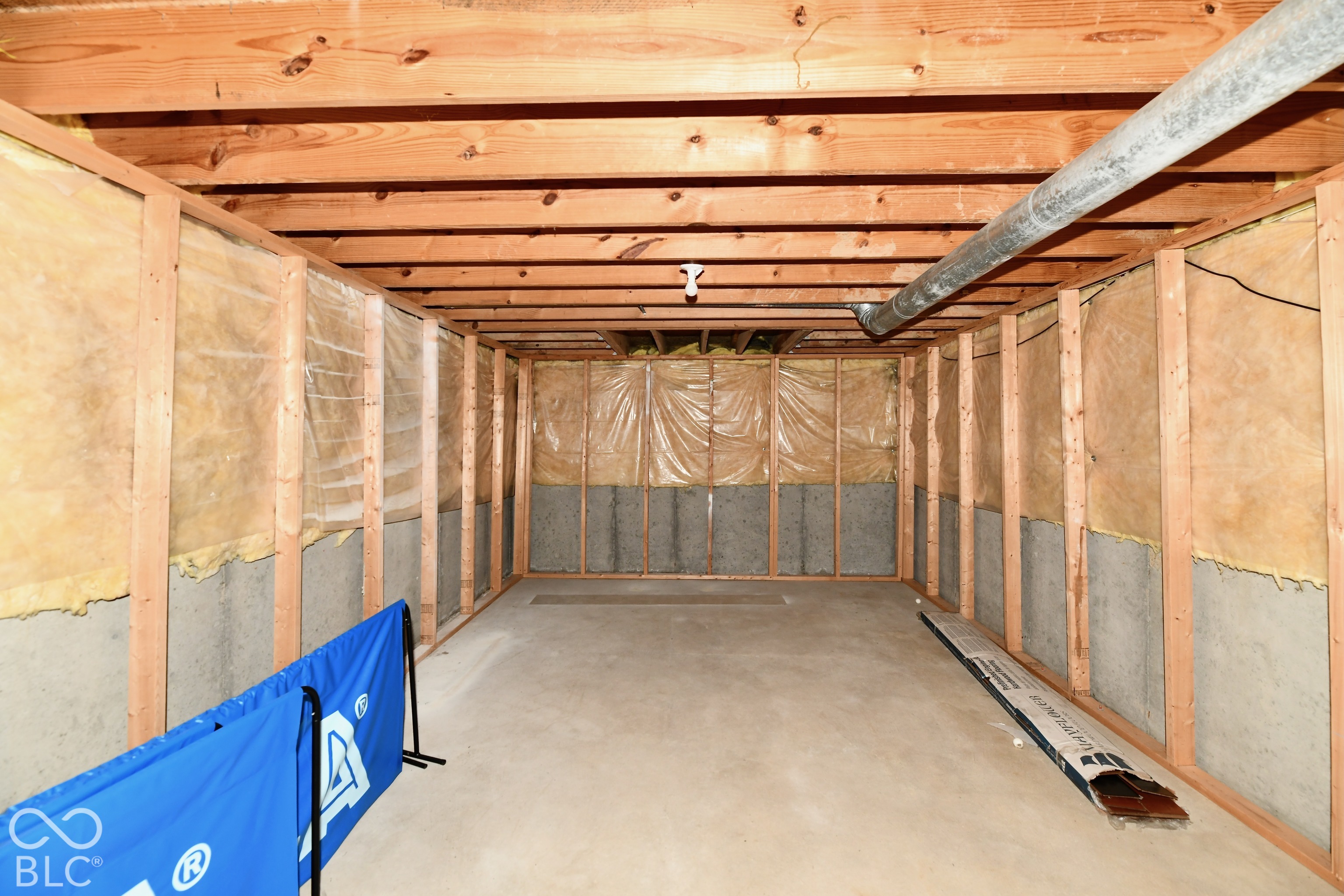 Unfinished area with exposed wood joists, poured concrete foundation walls, and stud-frame wall construction