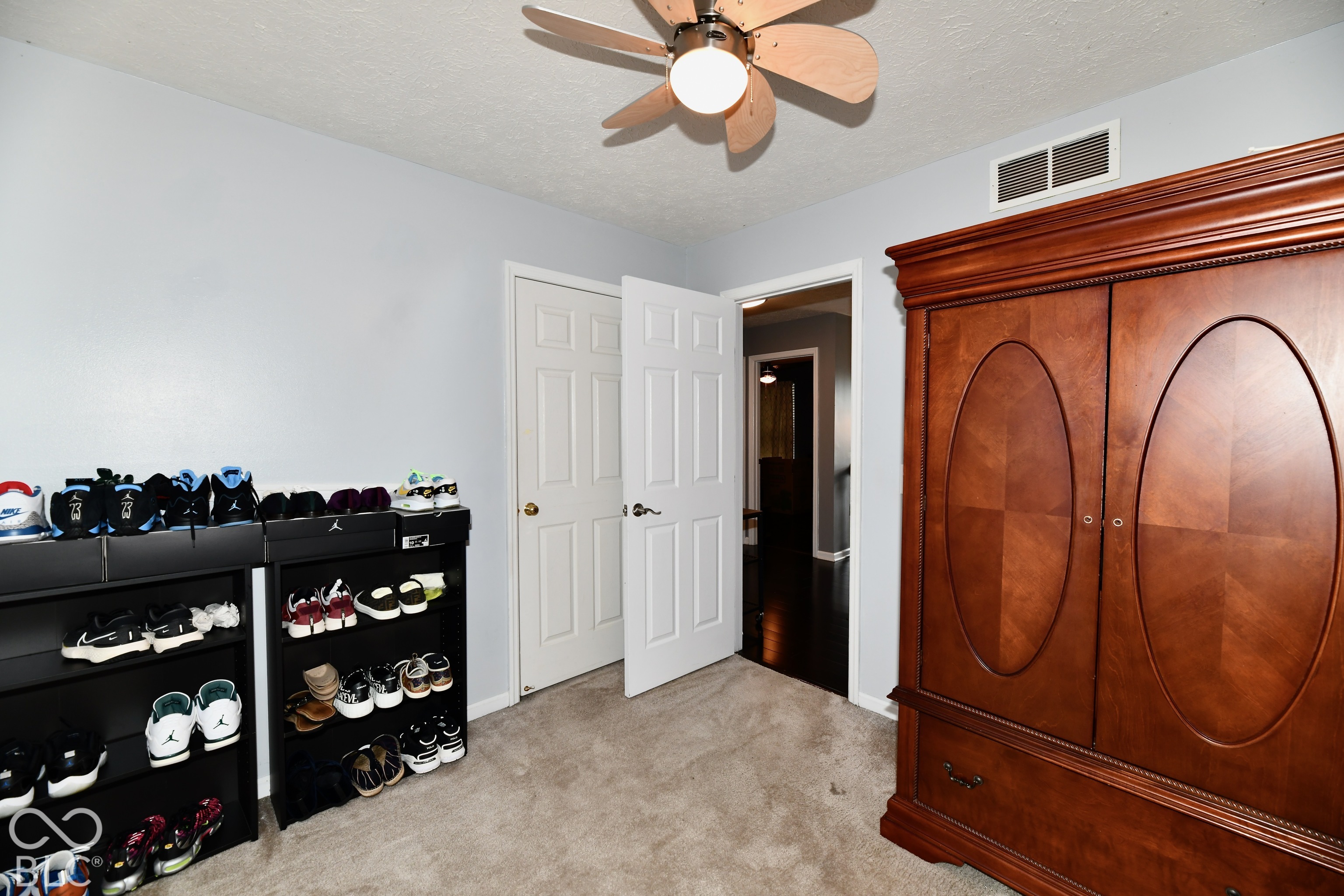 Interior space featuring neutral wall paint, carpeted flooring, a multi-blade ceiling fan with integrated lighting, and a six-panel interior door