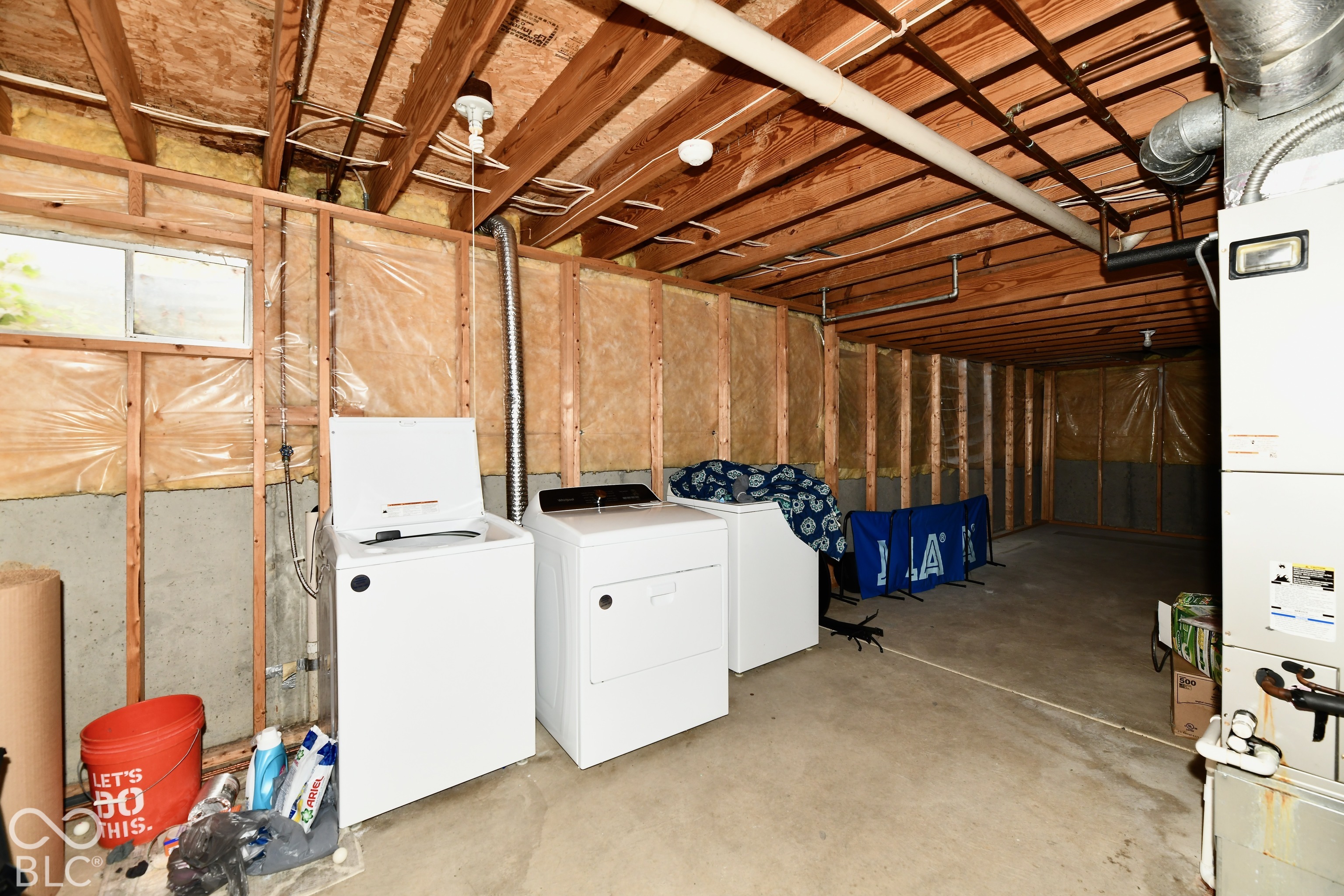 Unfinished lower level featuring exposed wood joists, concrete flooring, exterior-grade wall insulation, and a mechanical furnace system
