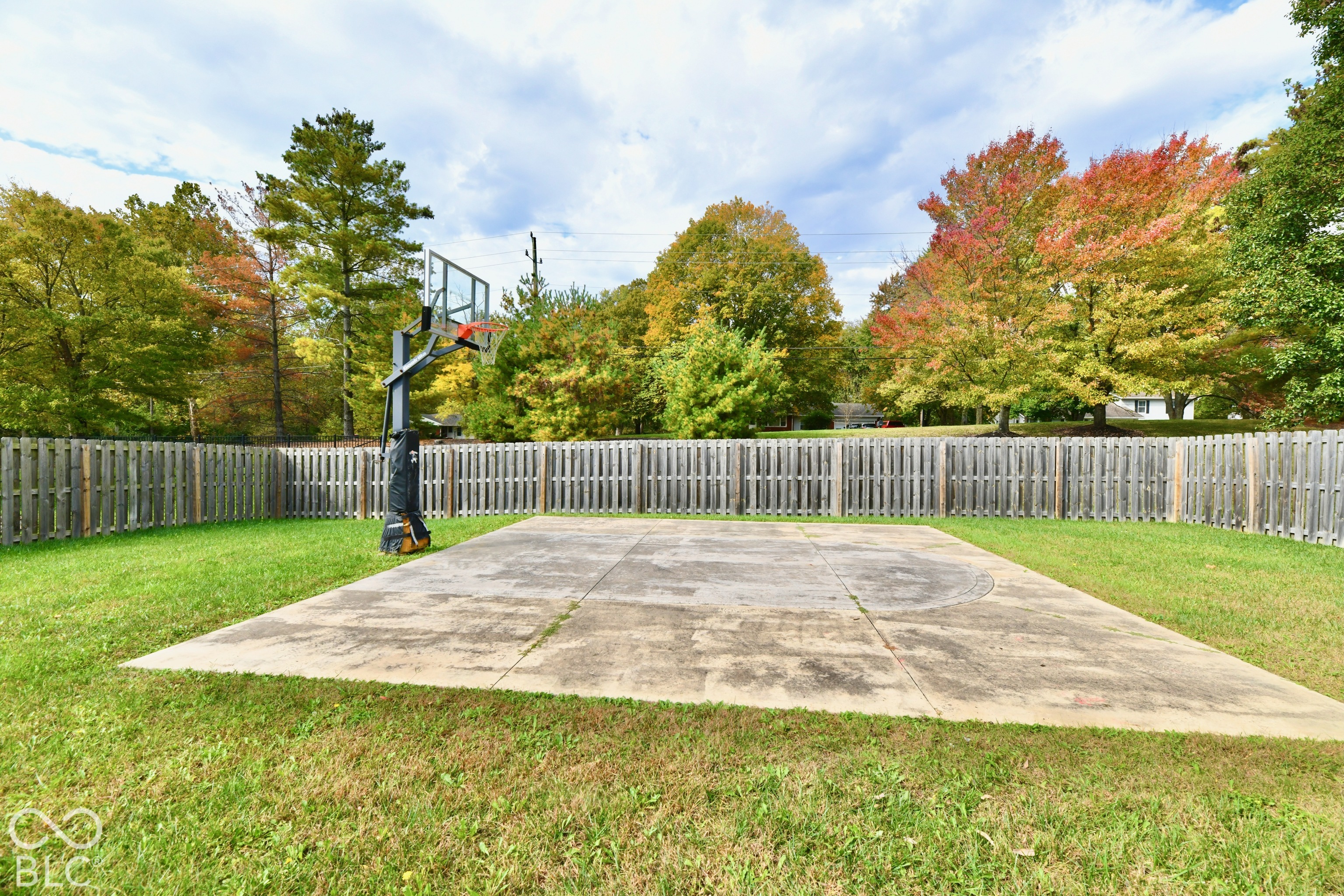 Backyard featuring a concrete basketball court, integrated hoop system, and wood-slat privacy fencing