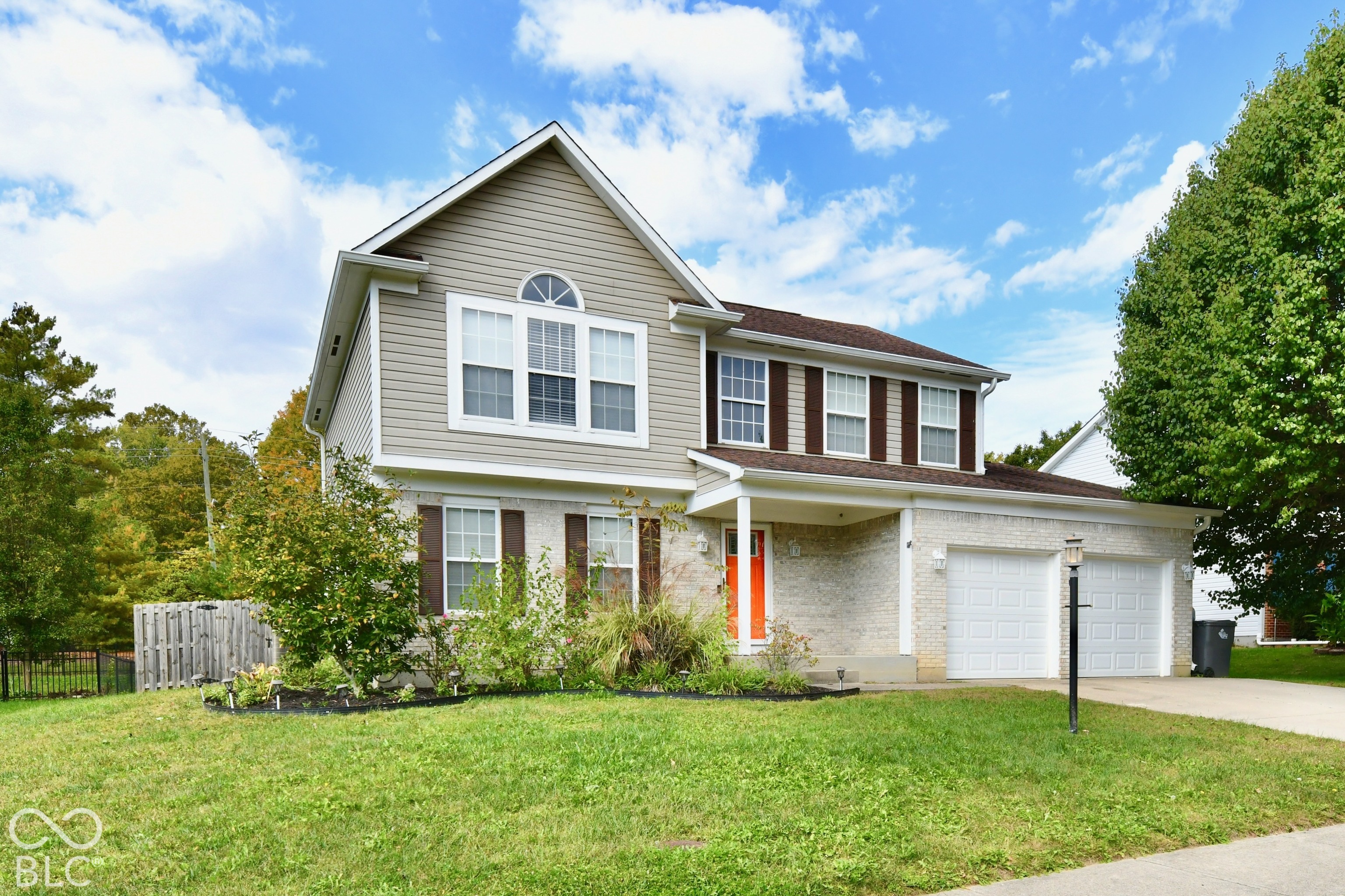 Two-story exterior featuring a brick and horizontal siding facade, a covered front porch, an attached two-car garage, and a decorative arched window Two-story exterior featuring a brick and horizontal siding facade, a covered front porch, an attached two-car garage, and a decorative arched window