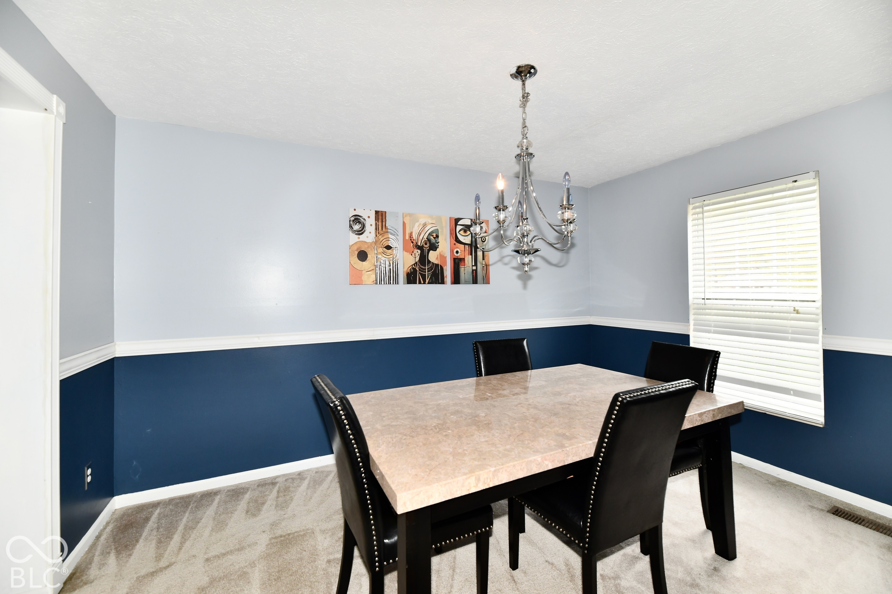 Dining area featuring two-tone wall paint, a chair rail, a multi-arm metal chandelier, and a horizontal window with blinds