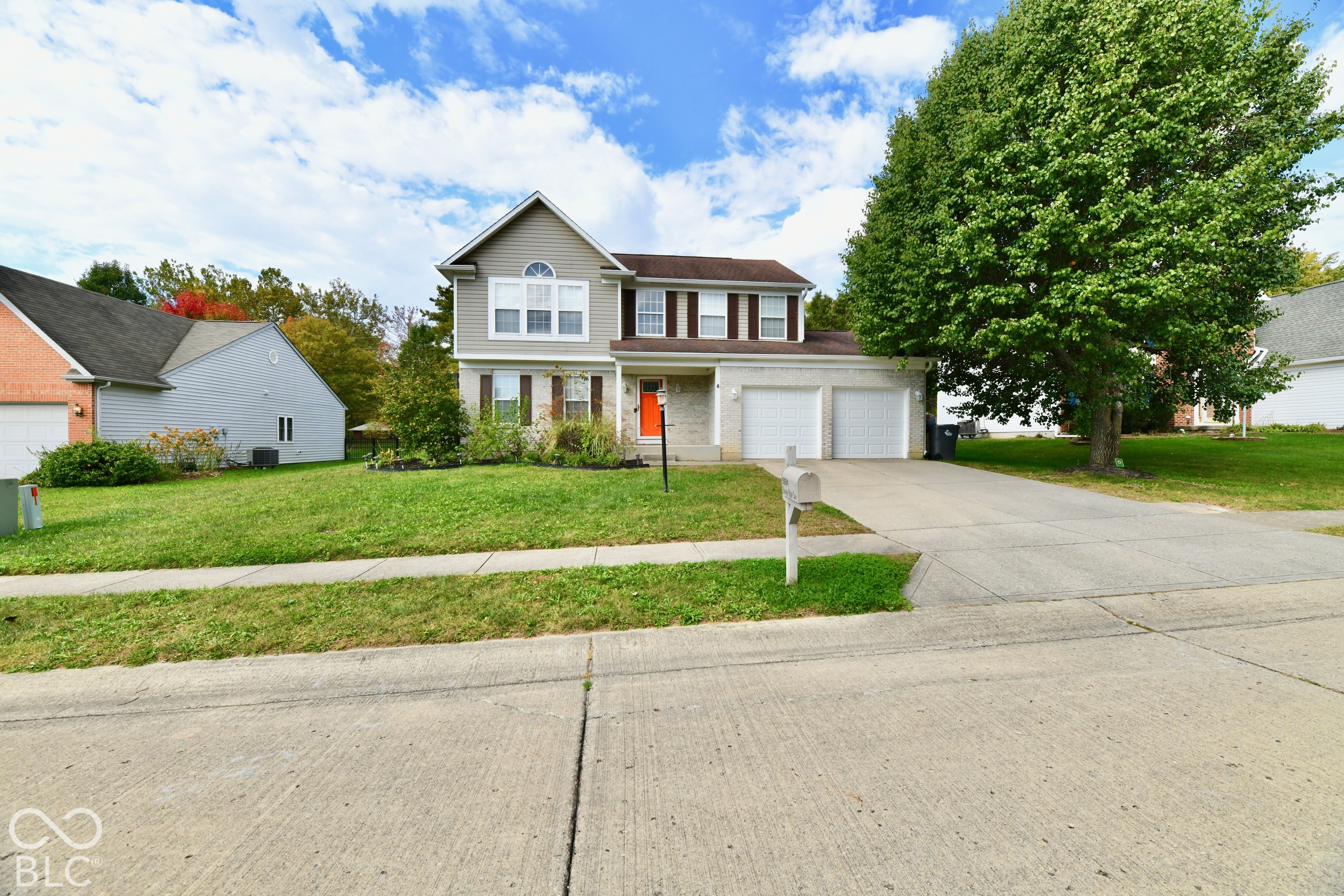 Two-story residence featuring a combination of light-colored siding and stone veneer, a dual-car garage, and a concrete driveway Two-story residence featuring a combination of light-colored siding and stone veneer, a dual-car garage, and a concrete driveway