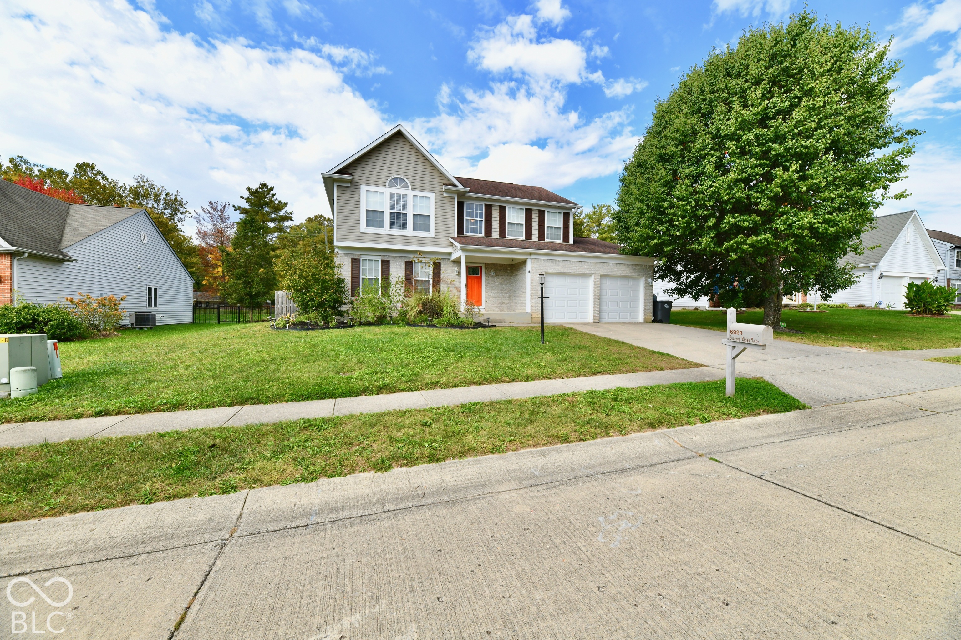 Two-story residence featuring light-toned masonry, vinyl siding, a multi-paneled front door, an attached two-car garage, and concrete driveway Two-story residence featuring light-toned masonry, vinyl siding, a multi-paneled front door, an attached two-car garage, and concrete driveway