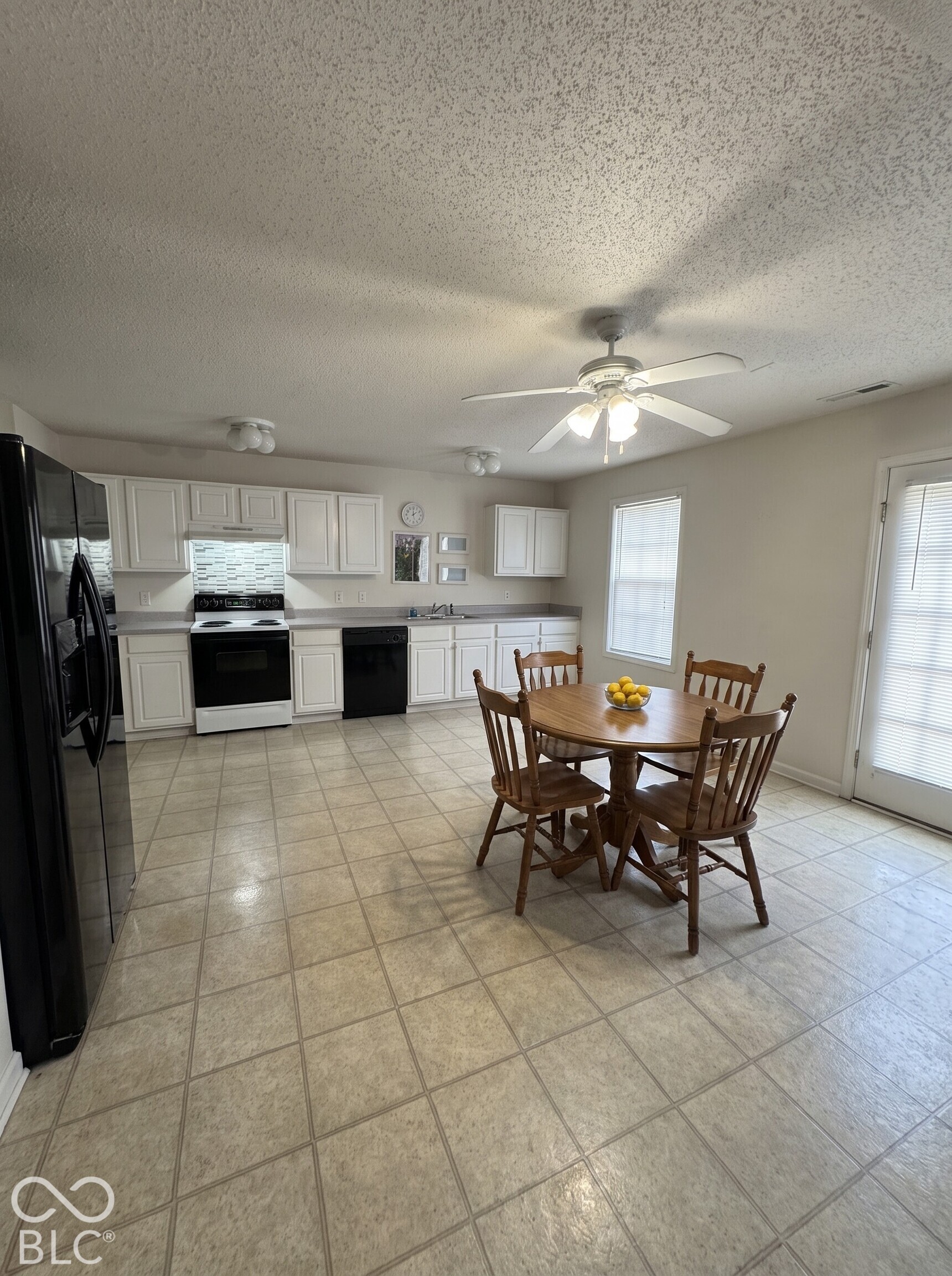 Virtually Altered - Kitchen featuring white cabinetry, black appliances, tile flooring, and a ceiling fan