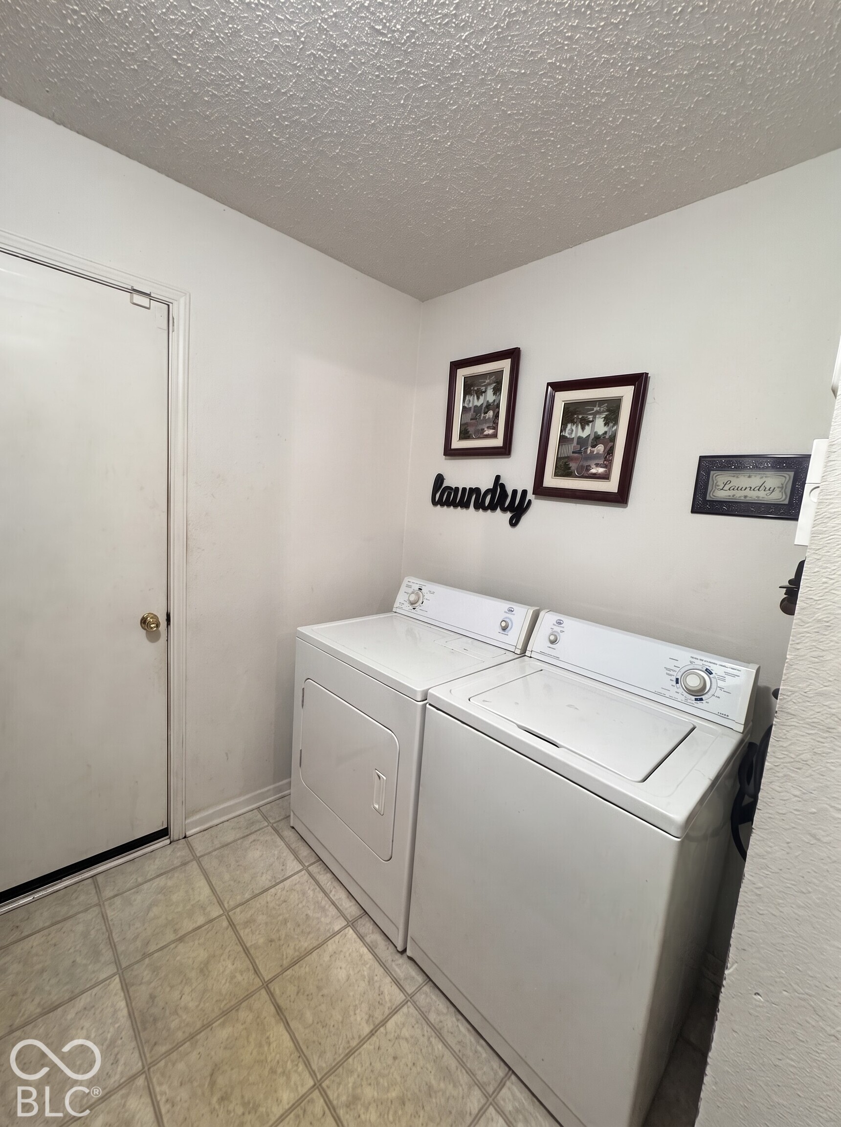 Virtually Altered - Utility space featuring ceramic tile flooring, a textured ceiling, and a full-size washer and dryer set