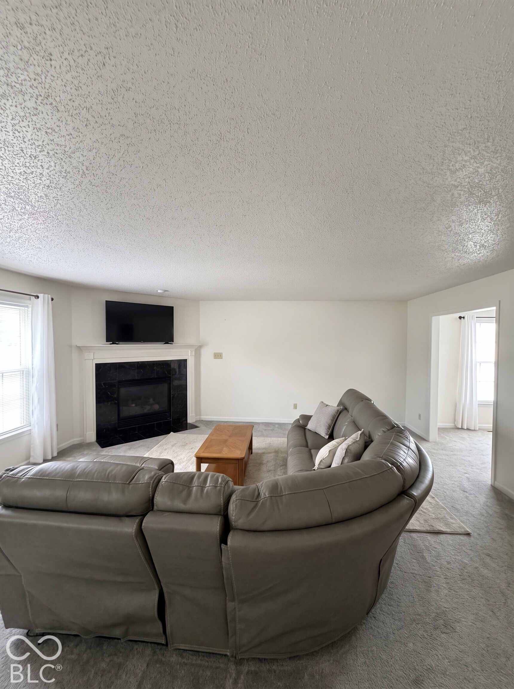 Virtually Altered - Corner fireplace featuring a black tile surround and a wood mantel