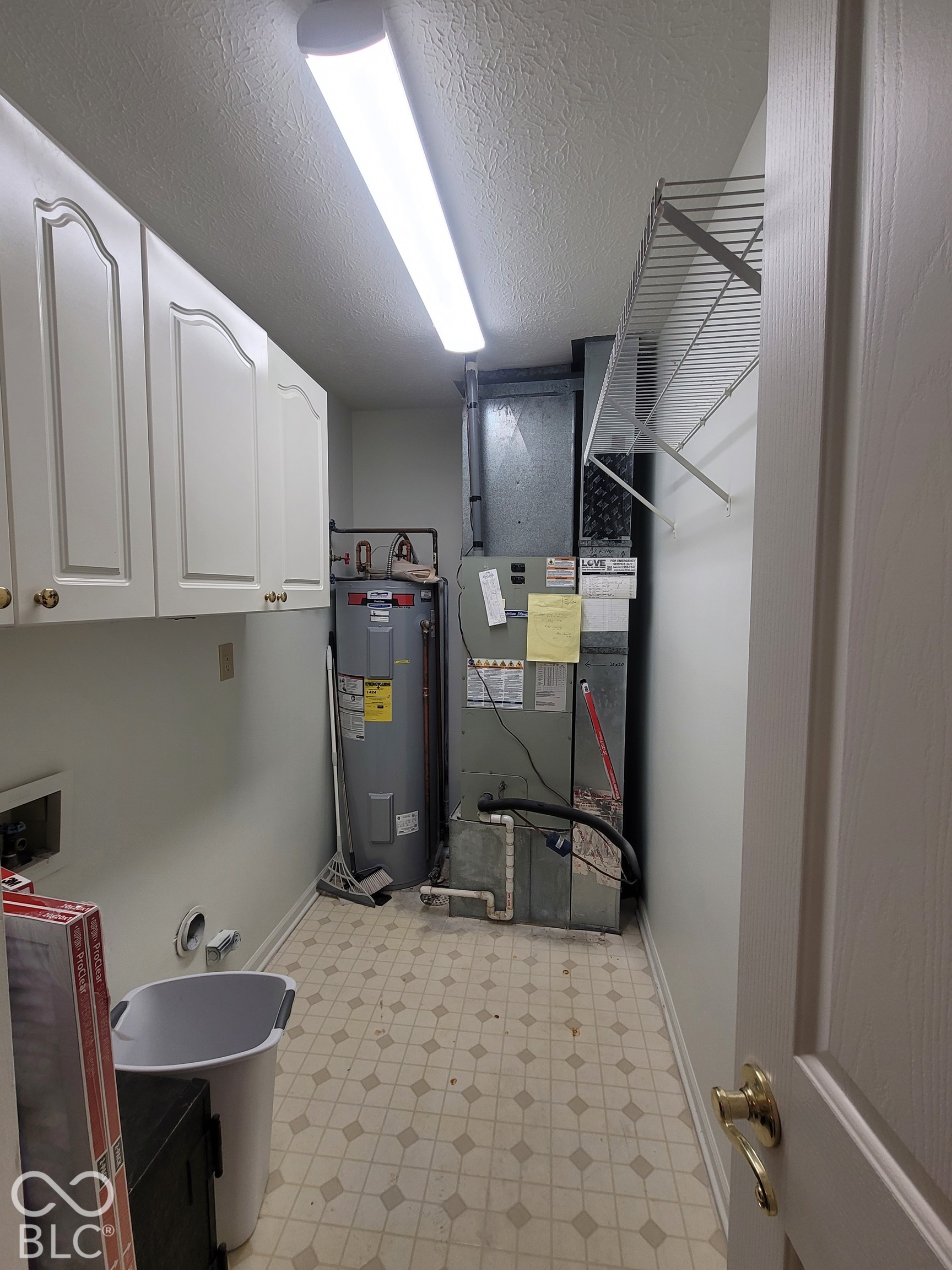 Utility area featuring white raised-panel upper cabinetry, a wire shelving unit, a vertical water heater, and a furnace