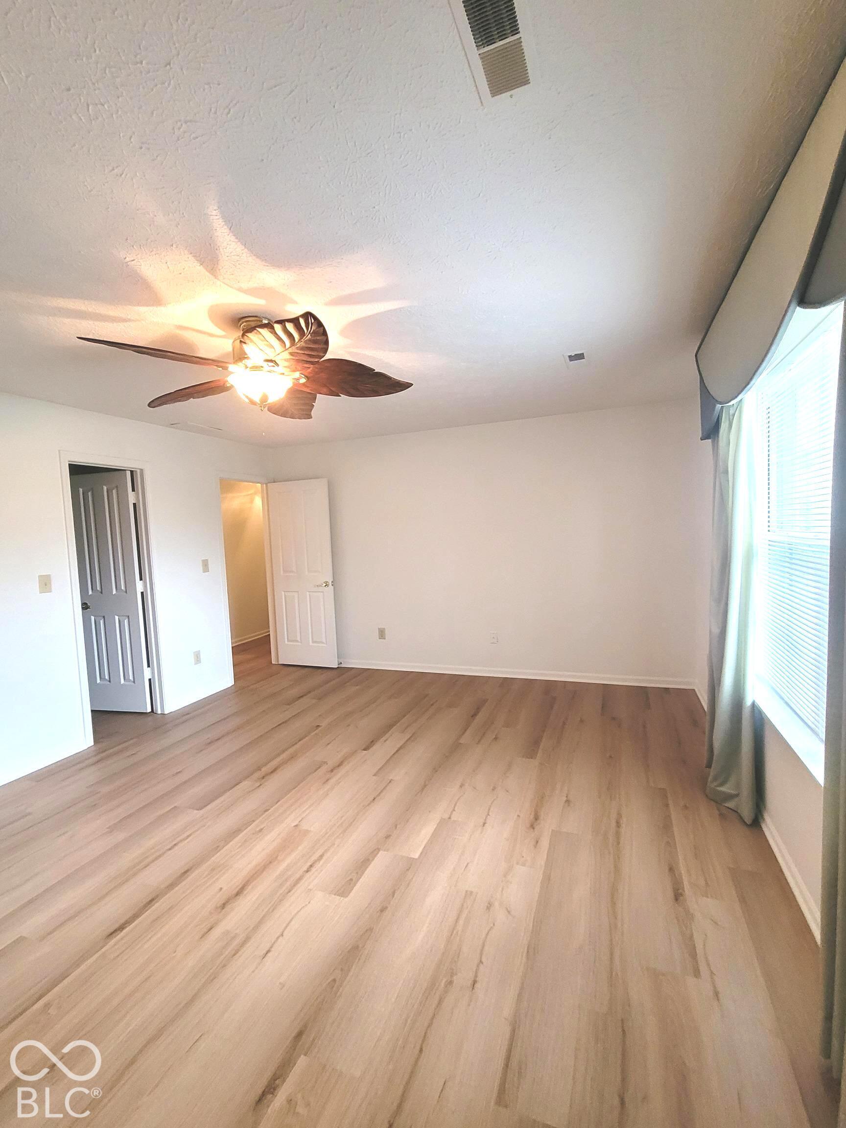 Light-toned wood-finish flooring, recessed lighting, ceiling fan with palm-leaf style blades, and multi-panel interior doors
