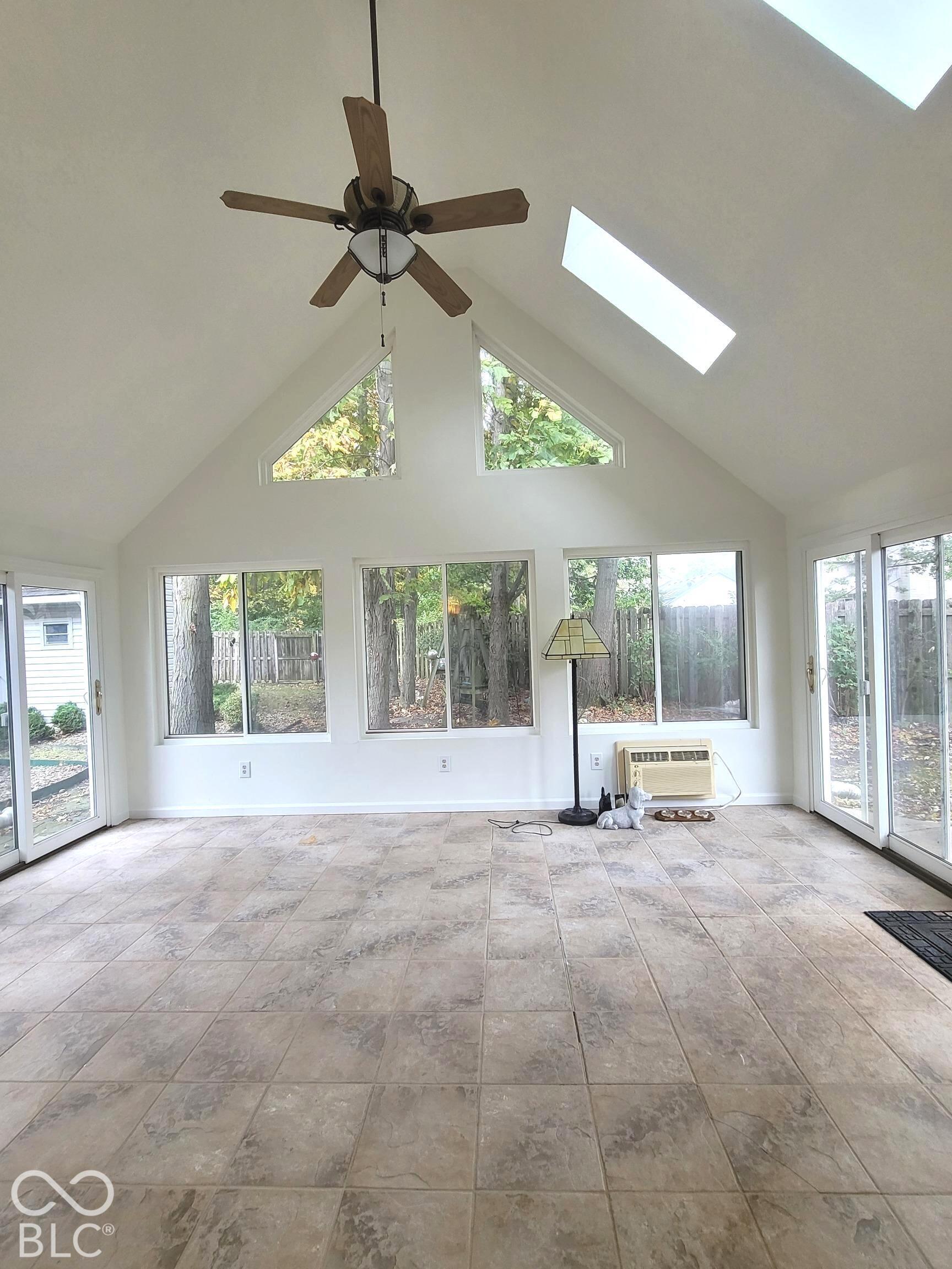 Vaulted ceilings with skylights, large picture windows, sliding glass doors, and tile flooring