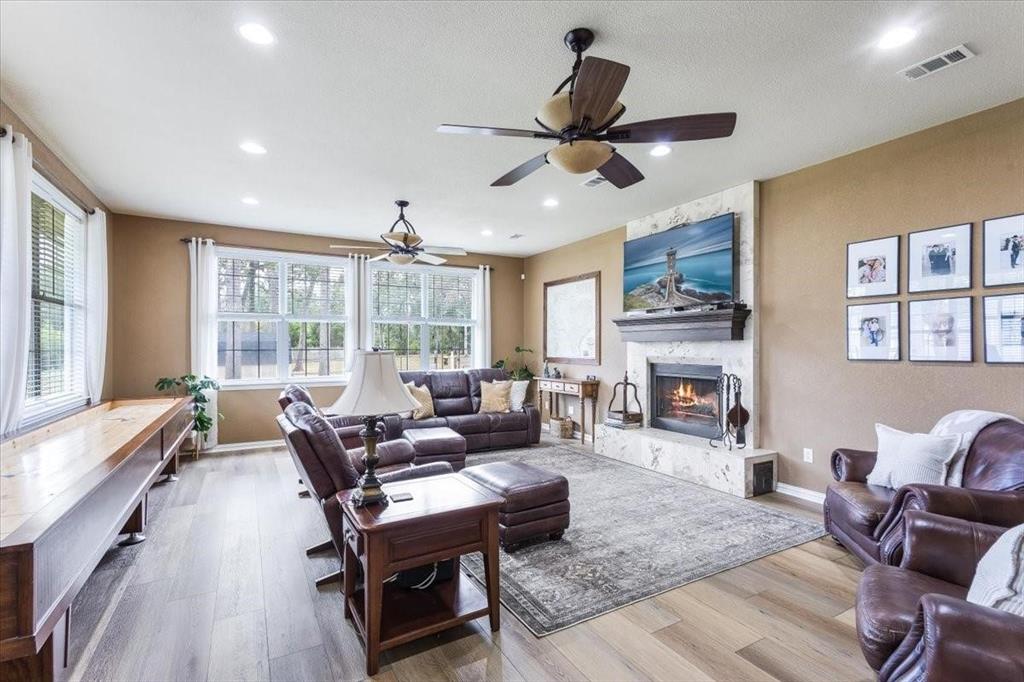 Living area featuring a large fireplace, baseboards, visible vents, and wood finished floors