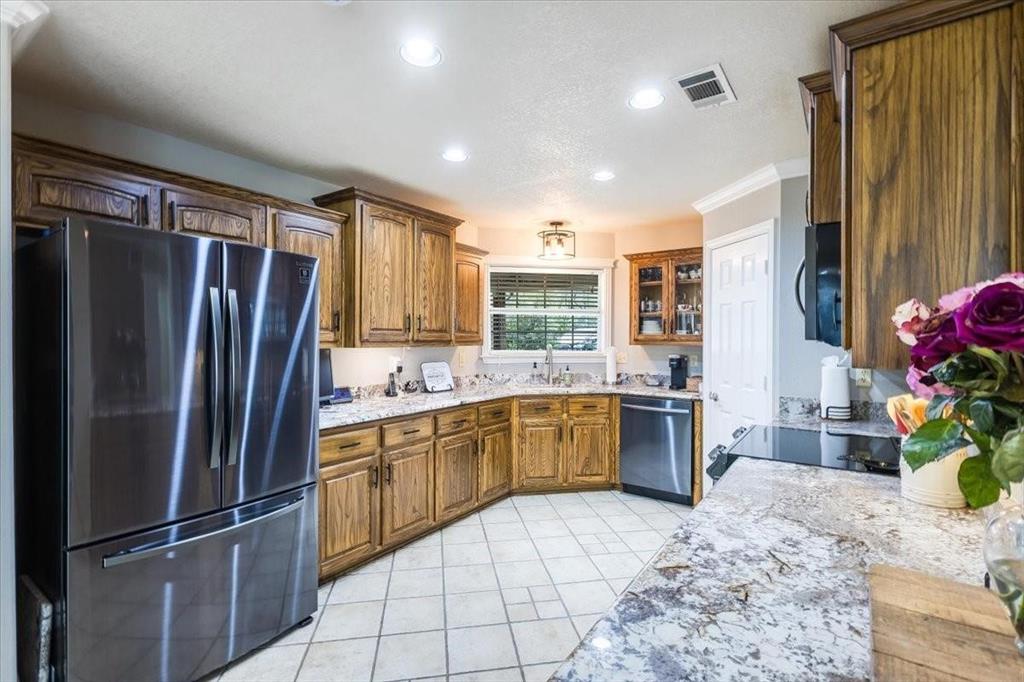 Kitchen featuring appliances with stainless steel finishes, brown cabinetry, visible vents, and a sink