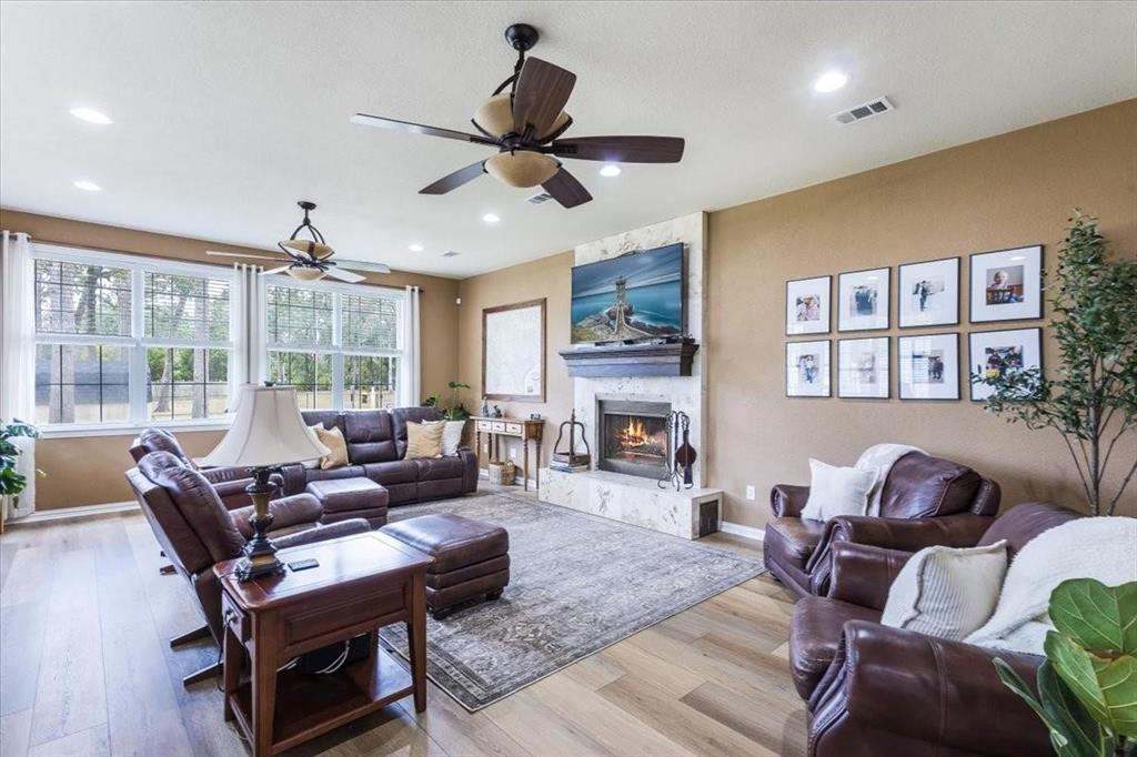 Living room featuring recessed lighting, visible vents, light wood-style floors, a stone fireplace, and baseboards Living room featuring recessed lighting, visible vents, light wood-style floors, a stone fireplace, and baseboards