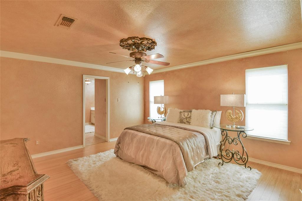 Bedroom featuring wood finished floors, a textured ceiling, ornamental molding, baseboards, and a ceiling fan