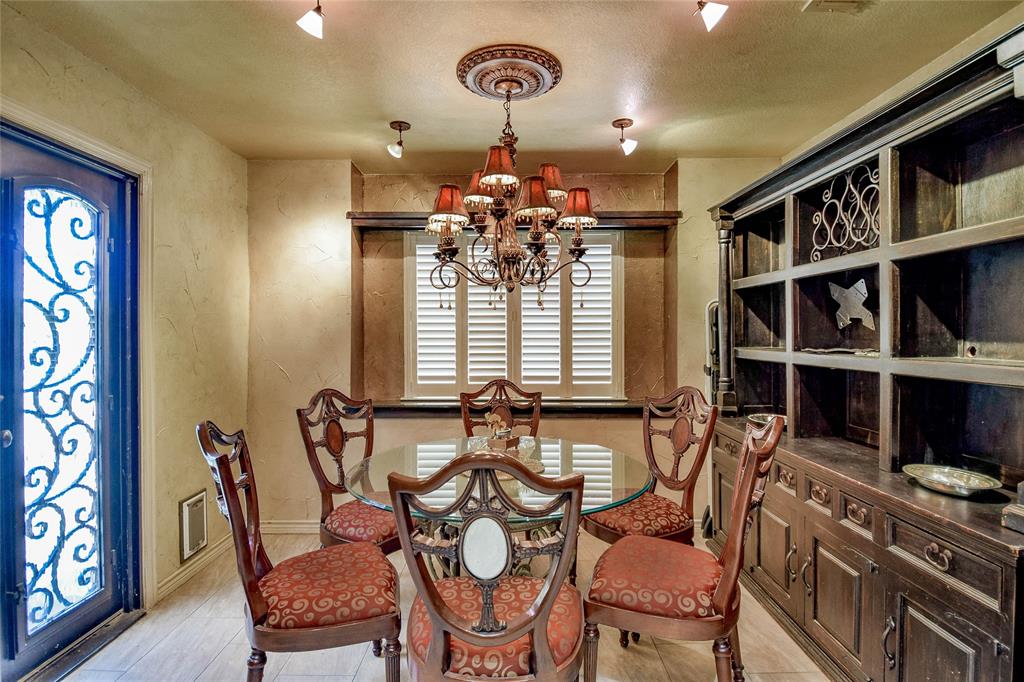 Dining area with a chandelier, baseboards, a textured wall, a textured ceiling, and light wood-type flooring