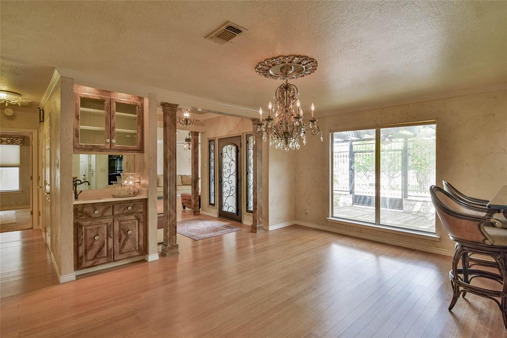 Unfurnished dining area featuring crown molding, a chandelier, light wood-style flooring, a textured ceiling, and baseboards