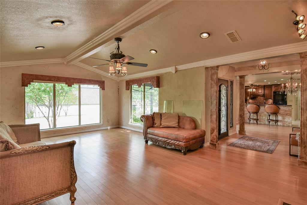 Living room with a ceiling fan, light wood-type flooring, a textured ceiling, ornamental molding, and baseboards