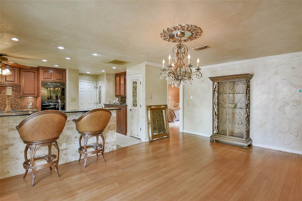Kitchen with a chandelier, brown cabinets, light wood-type flooring, glass insert cabinets, and dark countertops