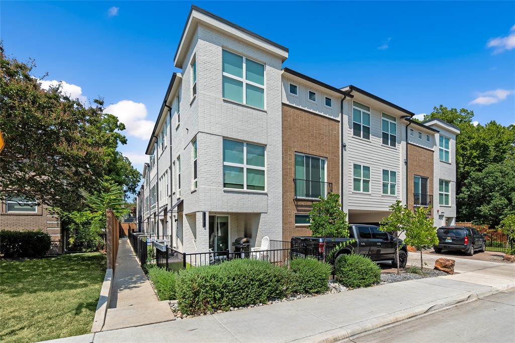 Multi-story townhouse exterior featuring a brick and siding facade, large grid windows, and a built-in covered parking area Multi-story townhouse exterior featuring a brick and siding facade, large grid windows, and a built-in covered parking area