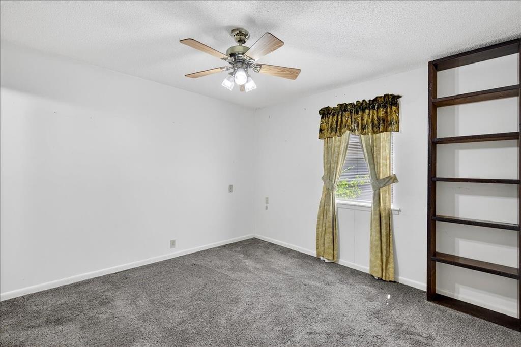 Carpeted empty room featuring a textured ceiling and a ceiling fan