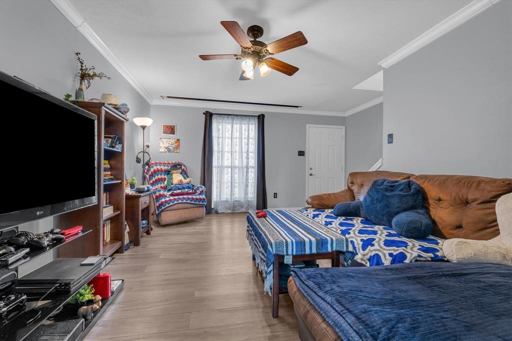 Bedroom with crown molding, ceiling fan, and light wood-style floors