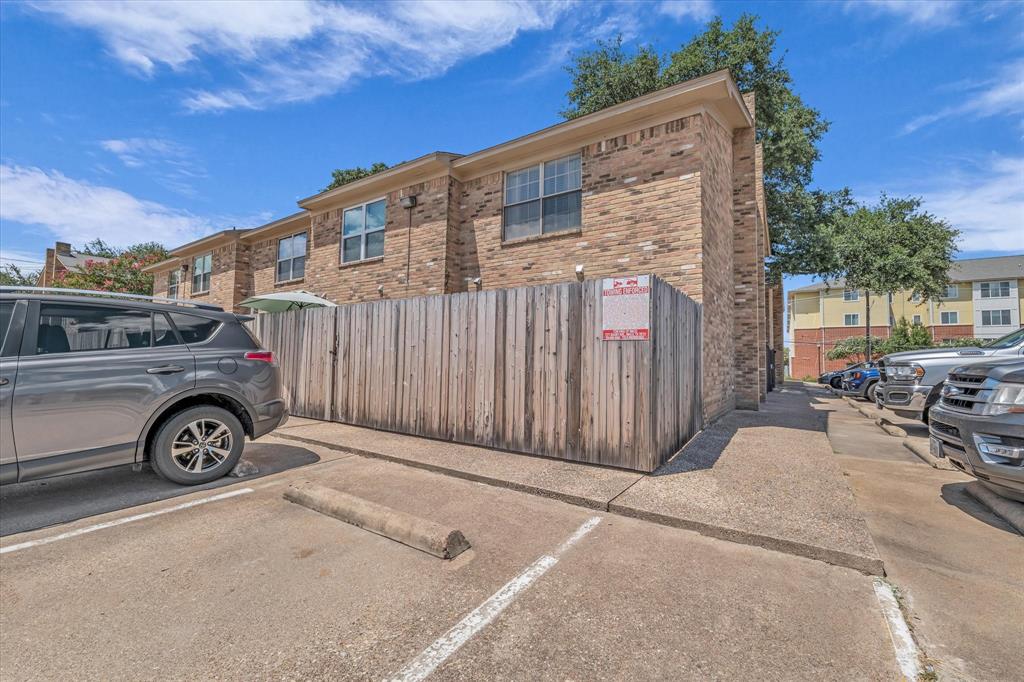 View of property exterior featuring uncovered parking and brick siding